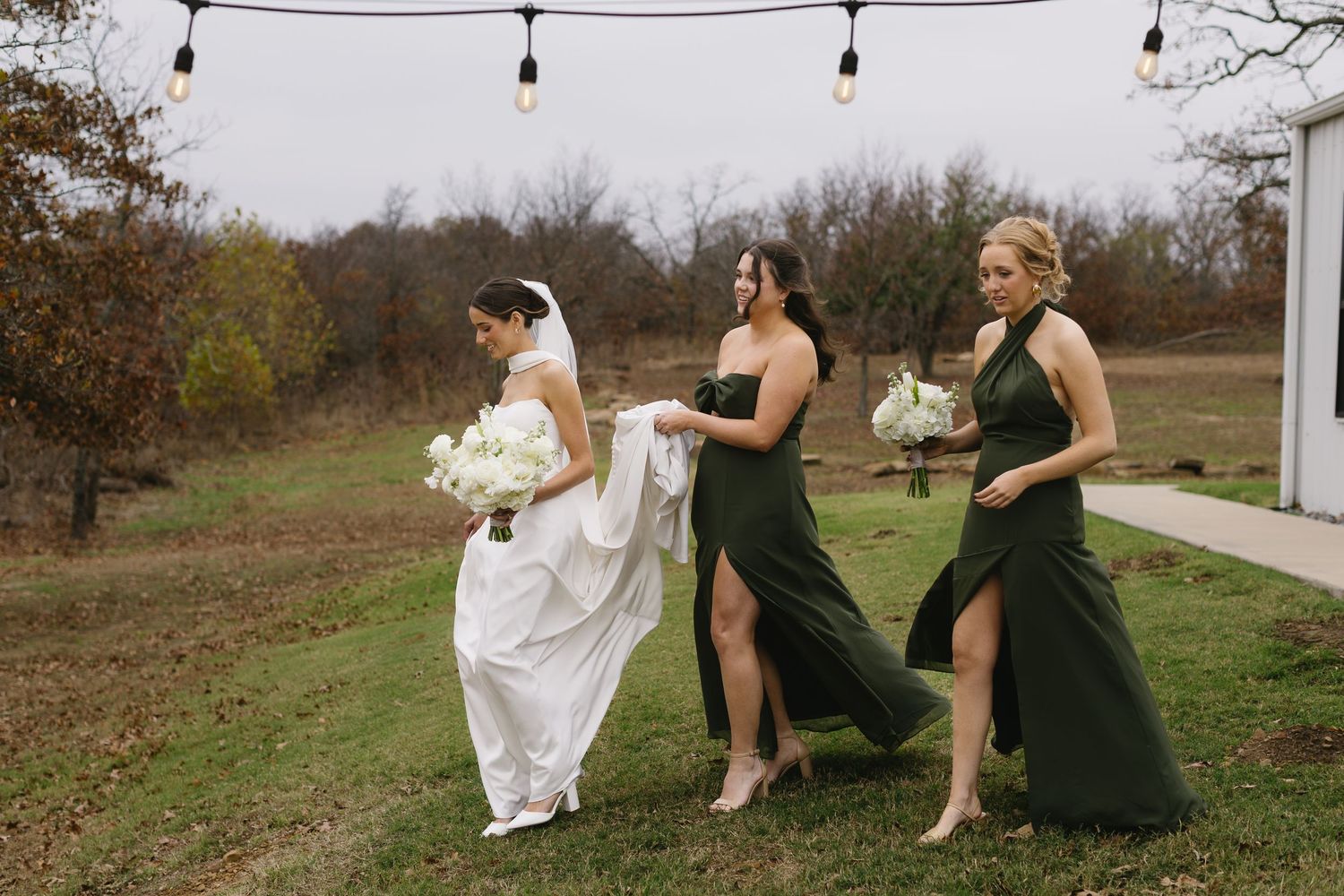 Wedding party relaxes on grass during outdoor autumn celebration.