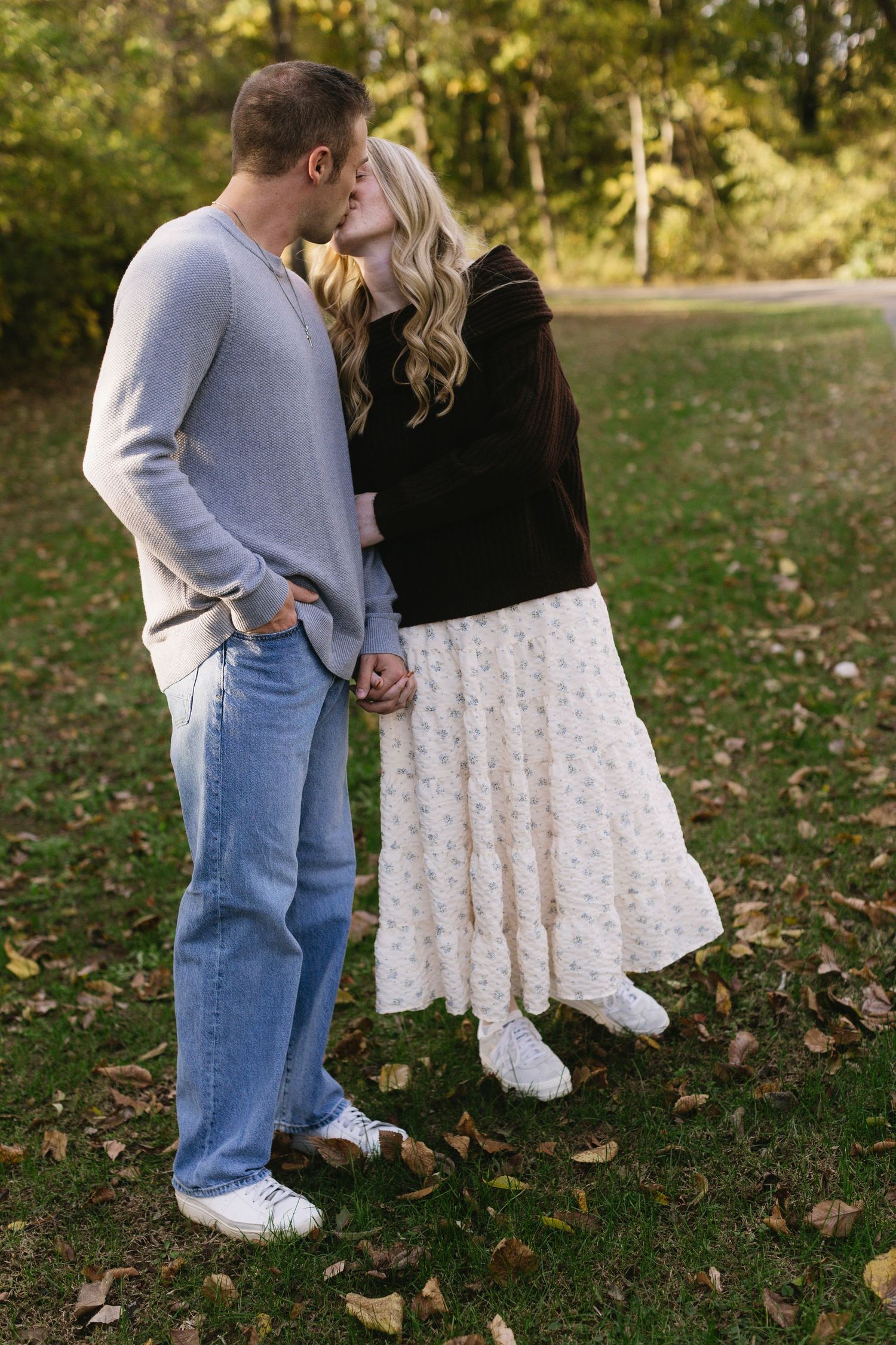 A couple shares playful moments together on fallen autumn leaves.