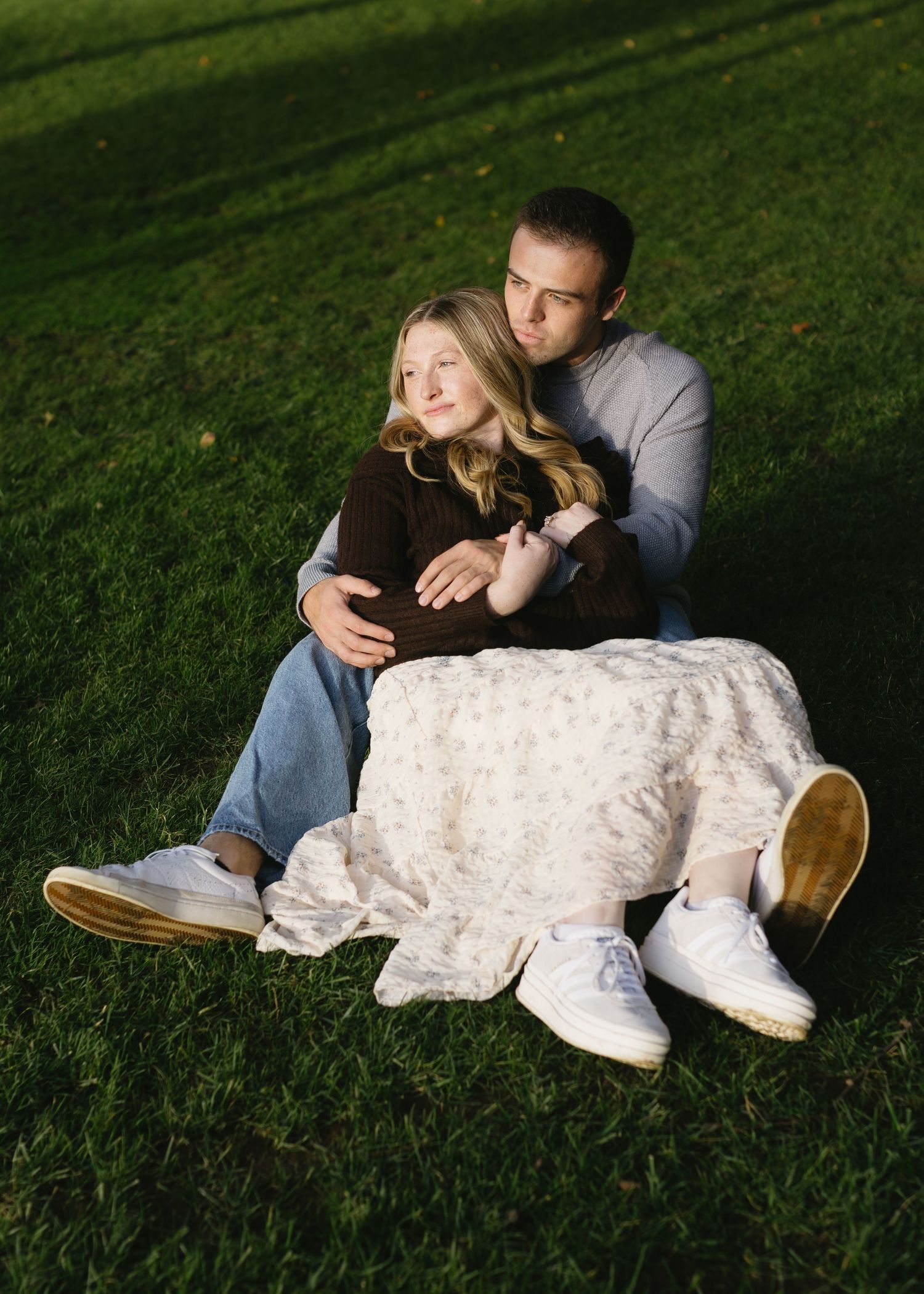 Two people relax together on green grass during sunset.