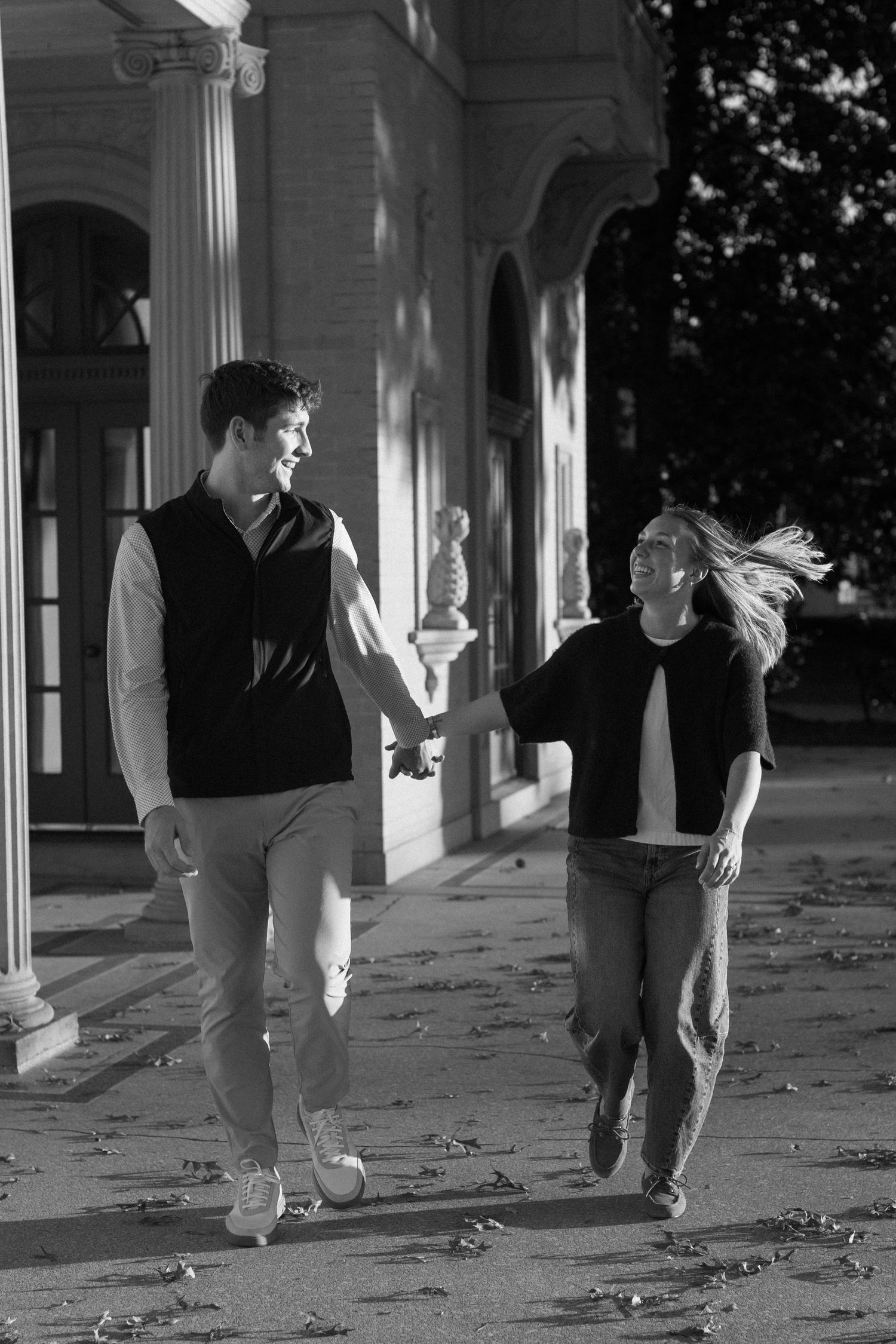 Couple walking together under classical columned architecture.