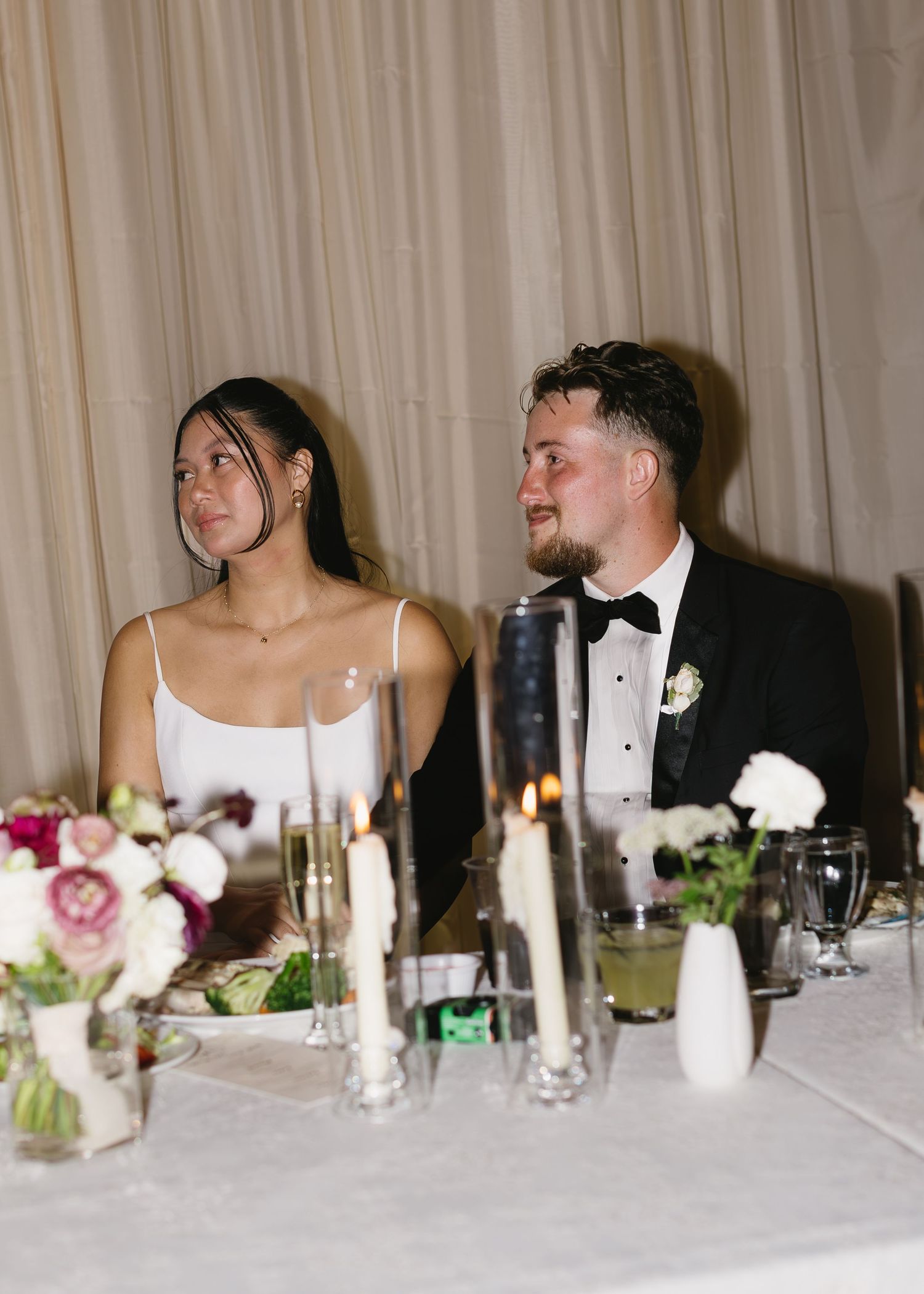 Wedding reception head table decorated with floral centerpieces and glowing candles.
