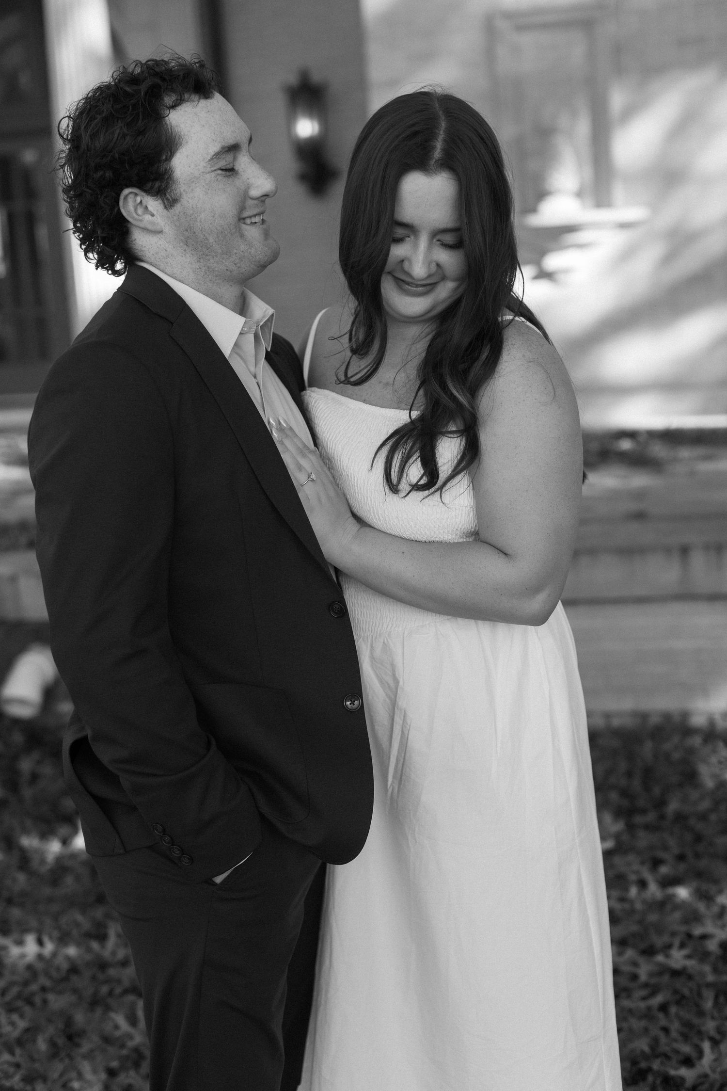 A romantic black and white portrait of a couple laughing together outdoors.