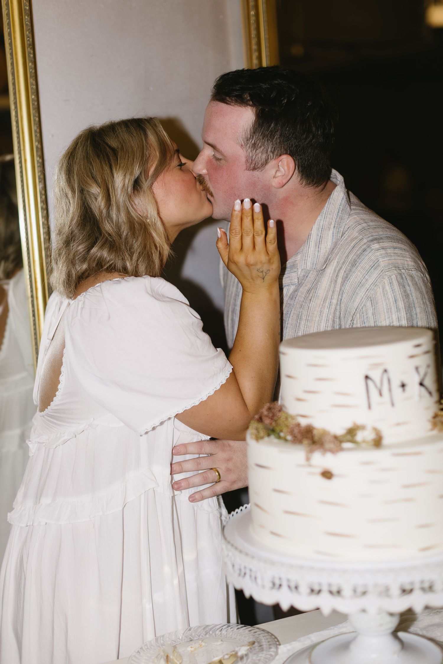 Wedding couple sharing a moment next to their white birch-themed wedding cake.