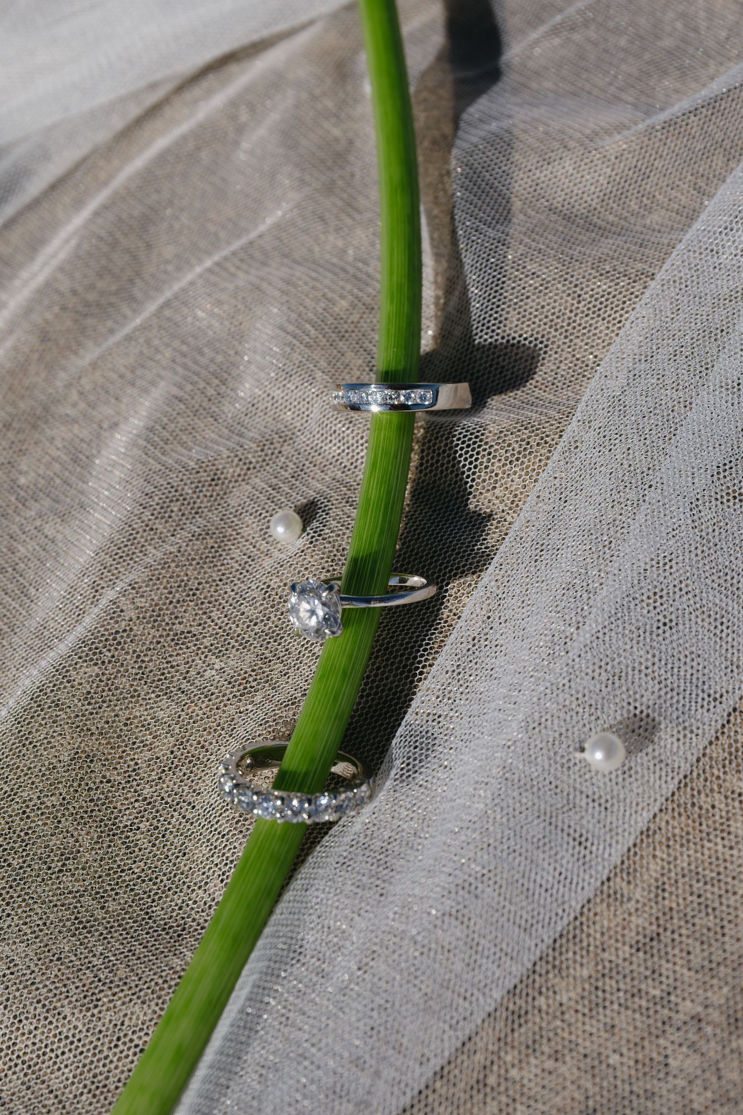 Wedding rings arranged with a white calla lily stem on delicate tulle fabric.