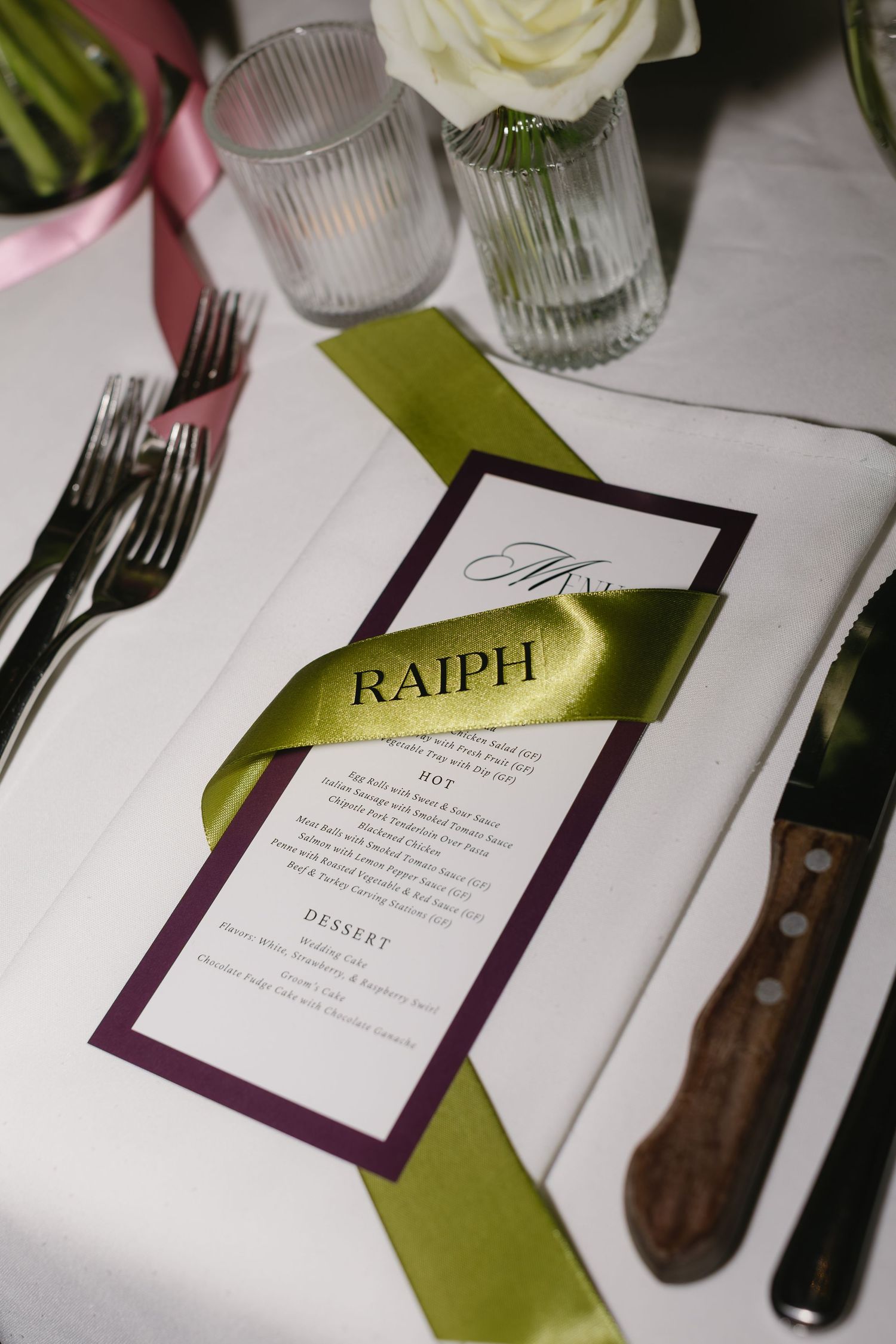 Elegant wedding reception place setting with menu cards in purple and green colors.