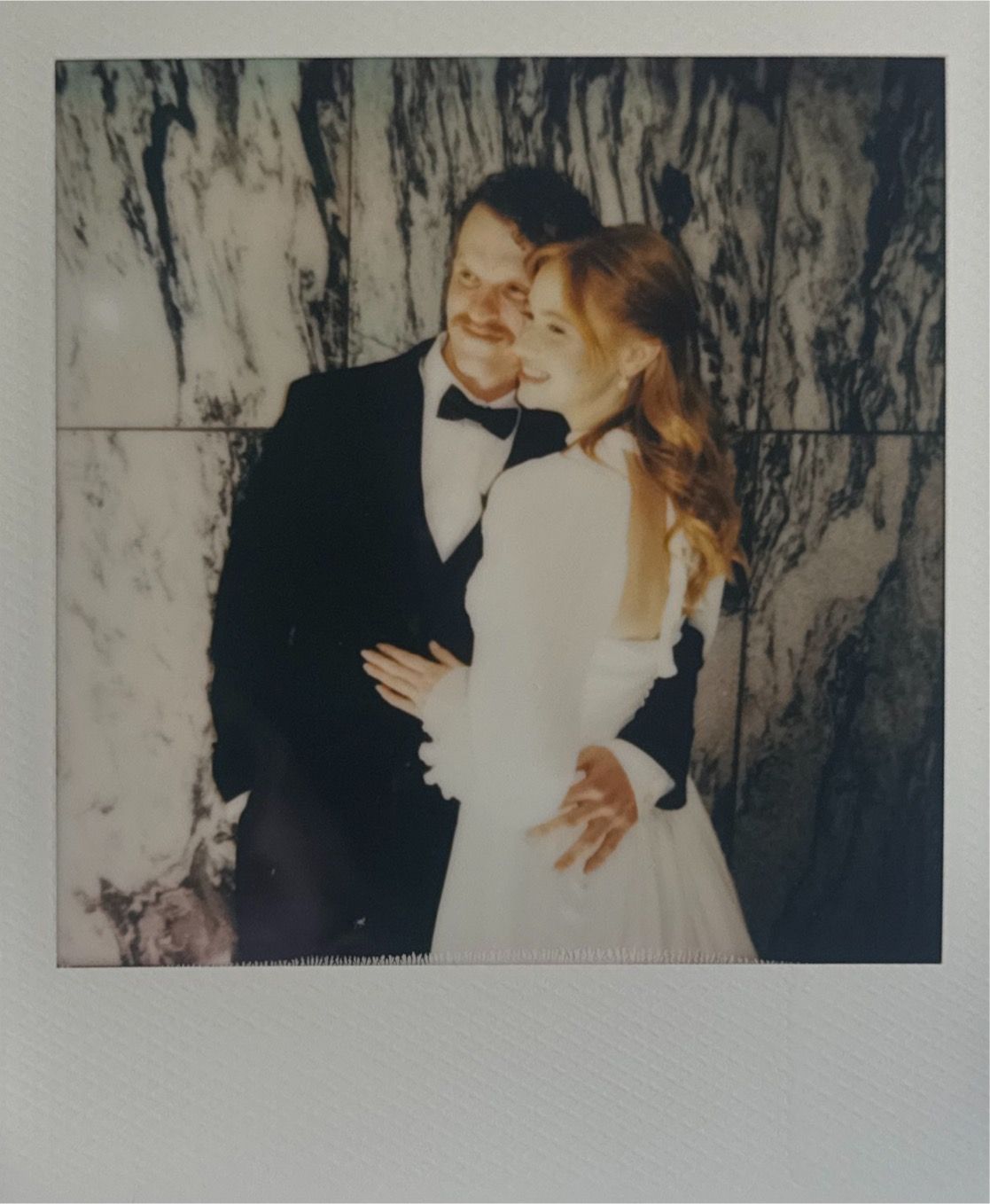 Vintage-style polaroid photos capture romantic wedding moments against a marble backdrop.