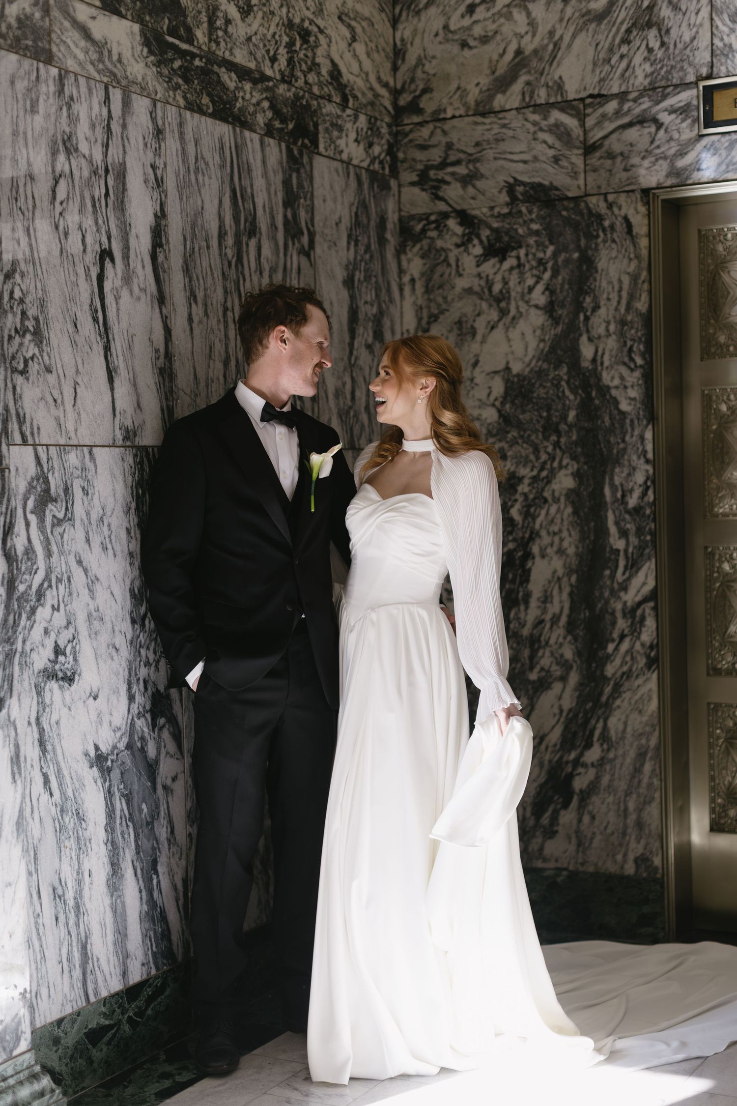 Elegant wedding couple poses in front of dramatic marble walls in a series of romantic shots.