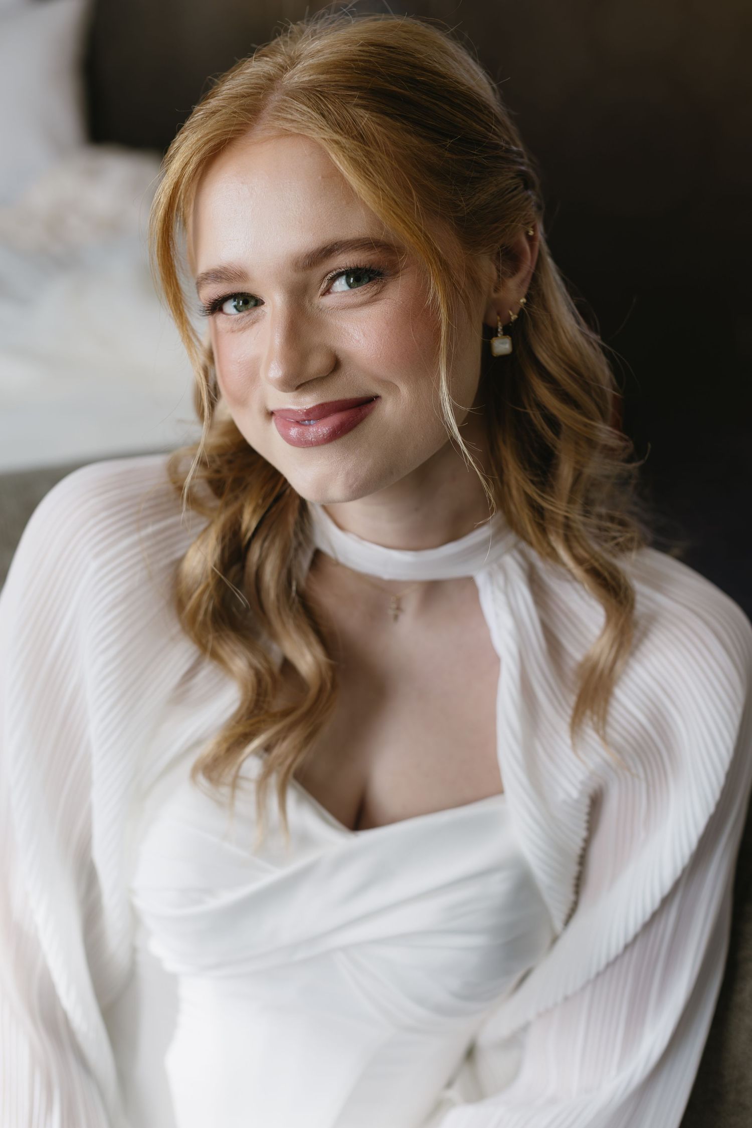Soft bridal portrait in natural light wearing white against dark background.