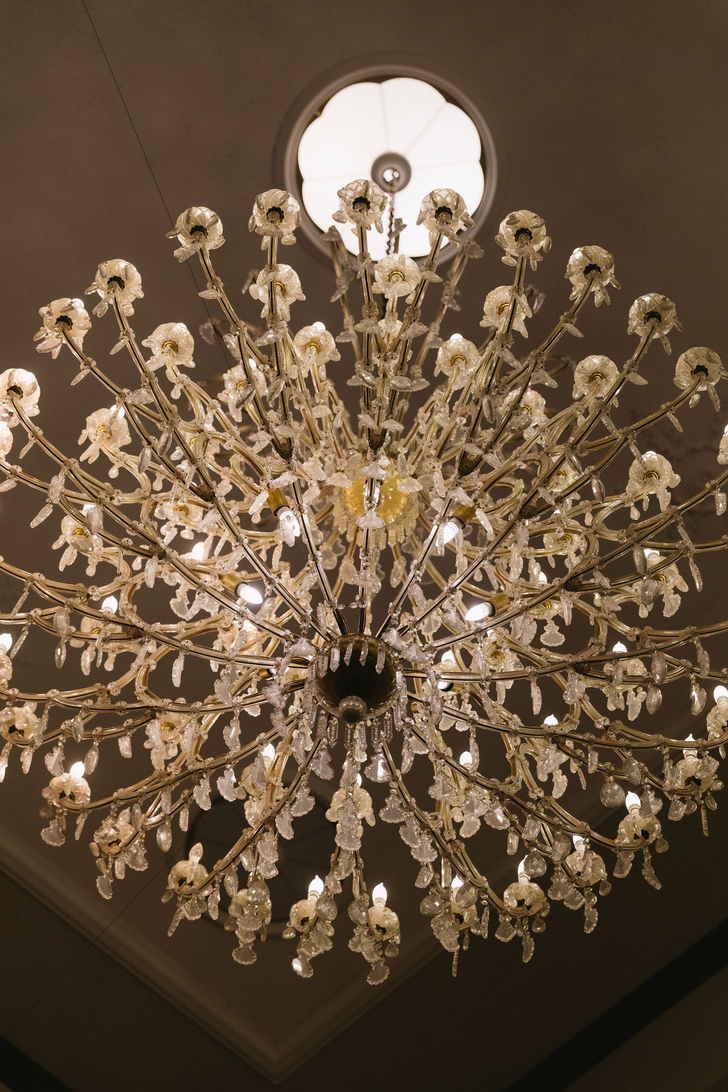 An elegant crystal chandelier with multiple tiers sparkles against a dark ceiling.