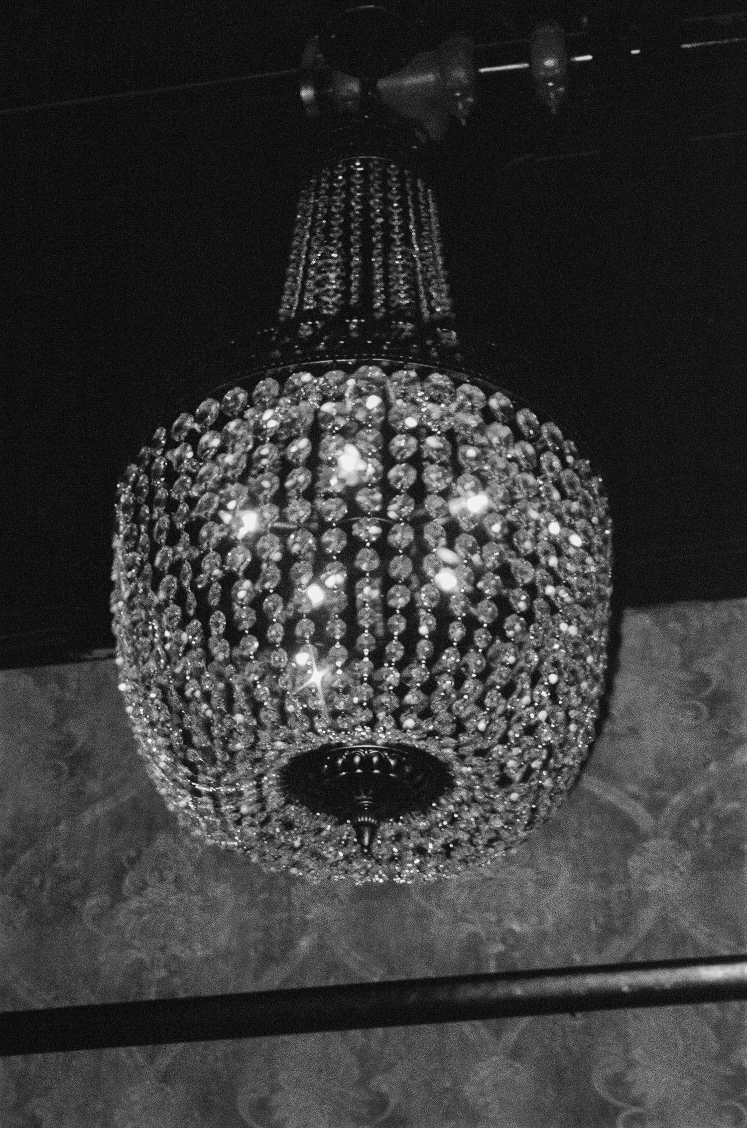 Close-up of a sparkling crystal chandelier casting dramatic light against a textured wall.