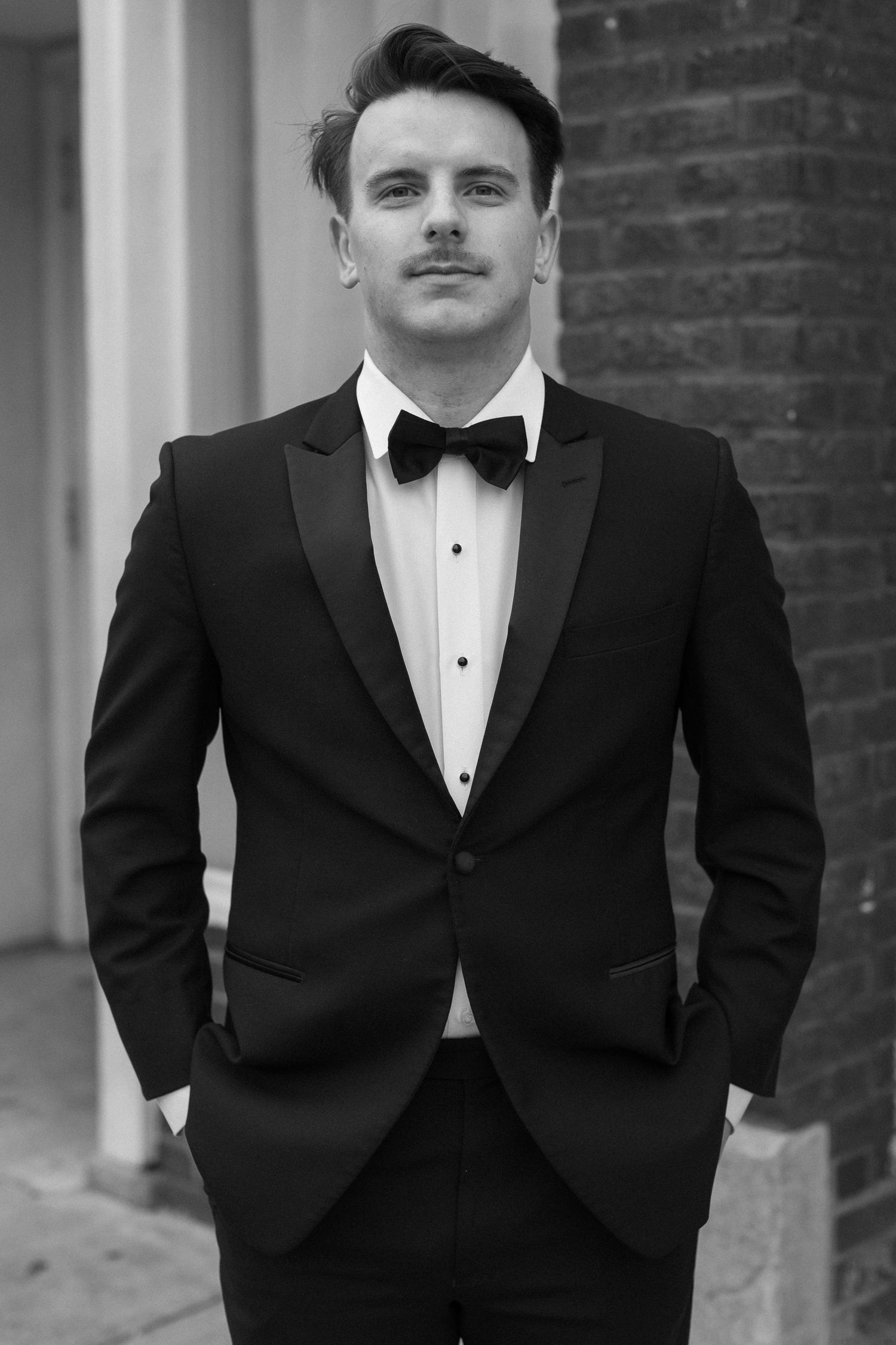 Classic black and white portrait of a groom in a tuxedo.