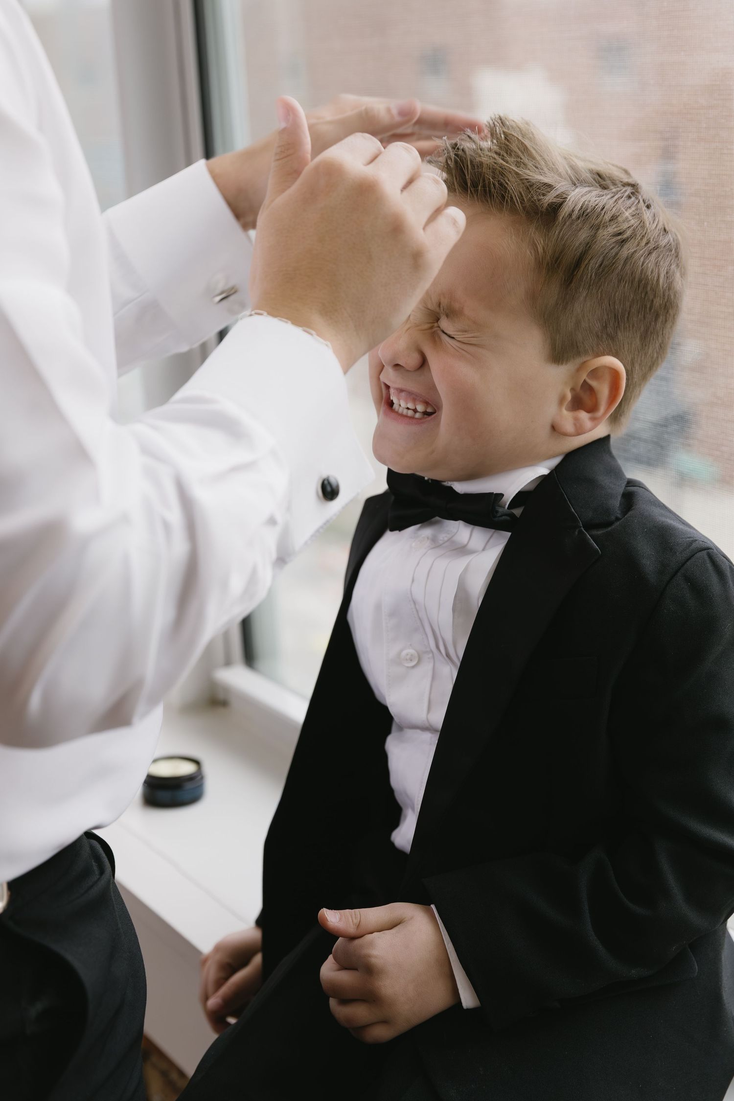 A joyful moment captured in formal attire near a bright window.