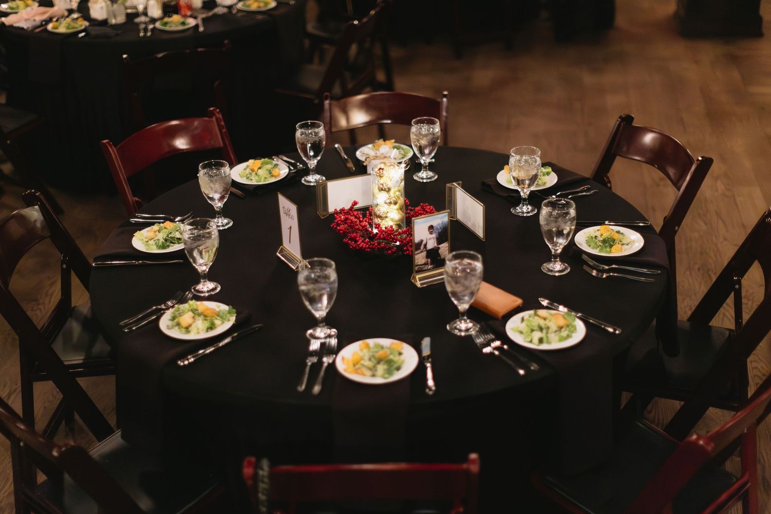 Dark restaurant interior showing several occupied tables with place settings and ambient lighting.