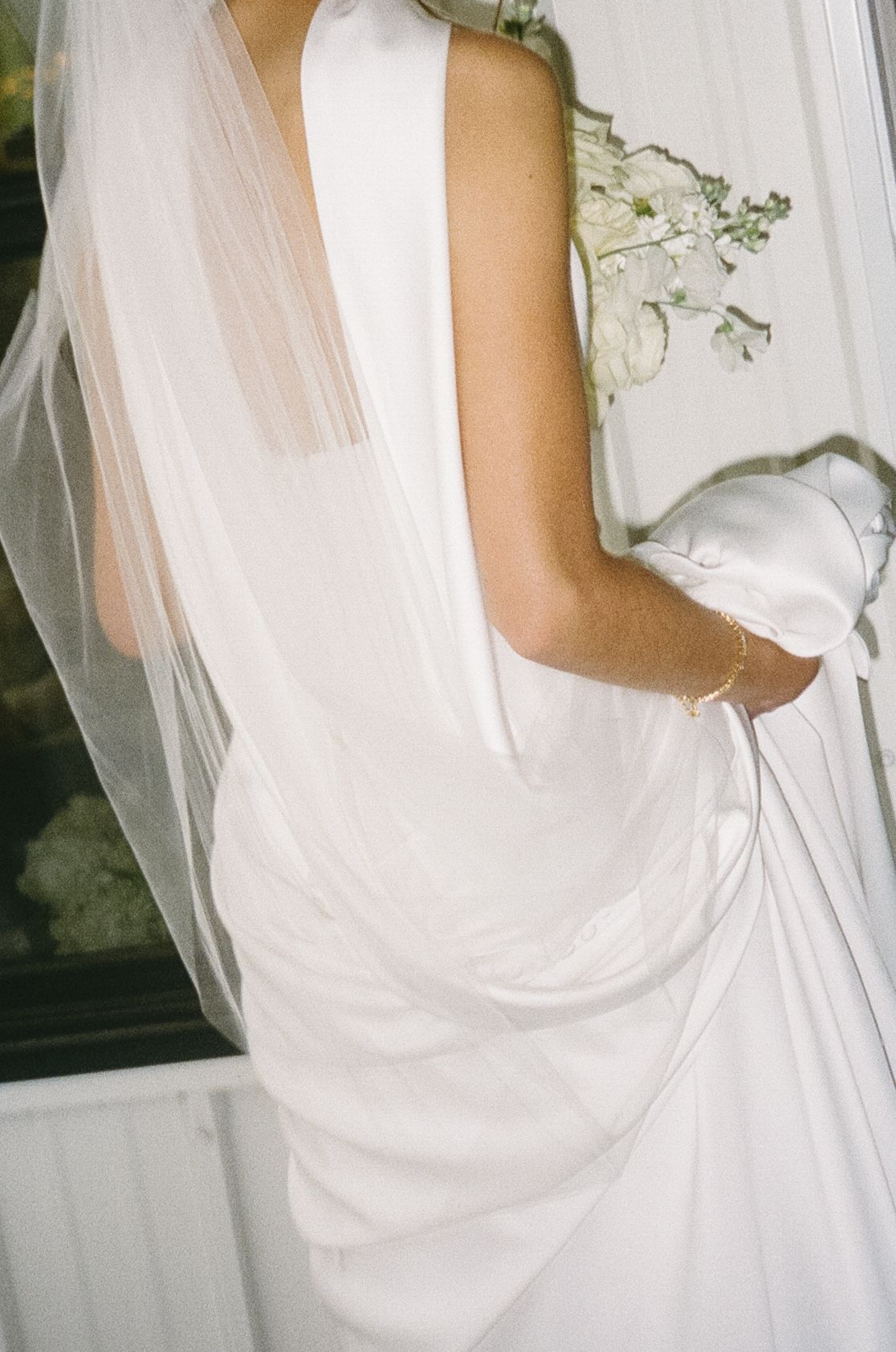 Close-up detail of a white wedding dress with flowing veil and delicate fabric.
