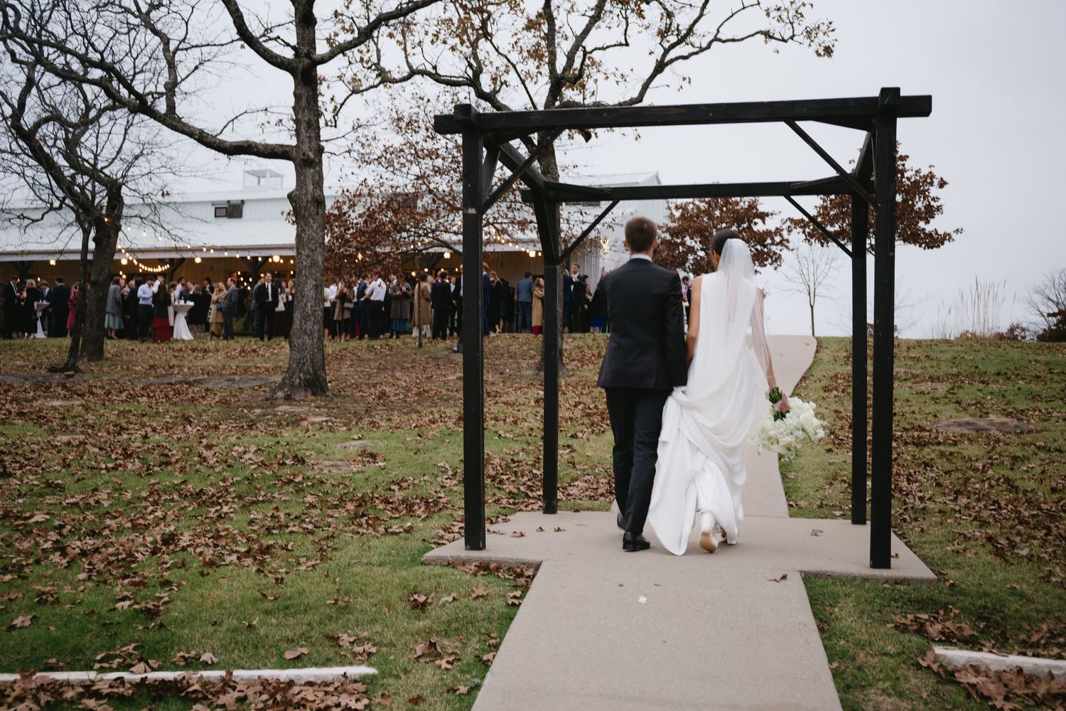 Wedding ceremony setup with wooden pergola and pathway in an autumn outdoor setting.