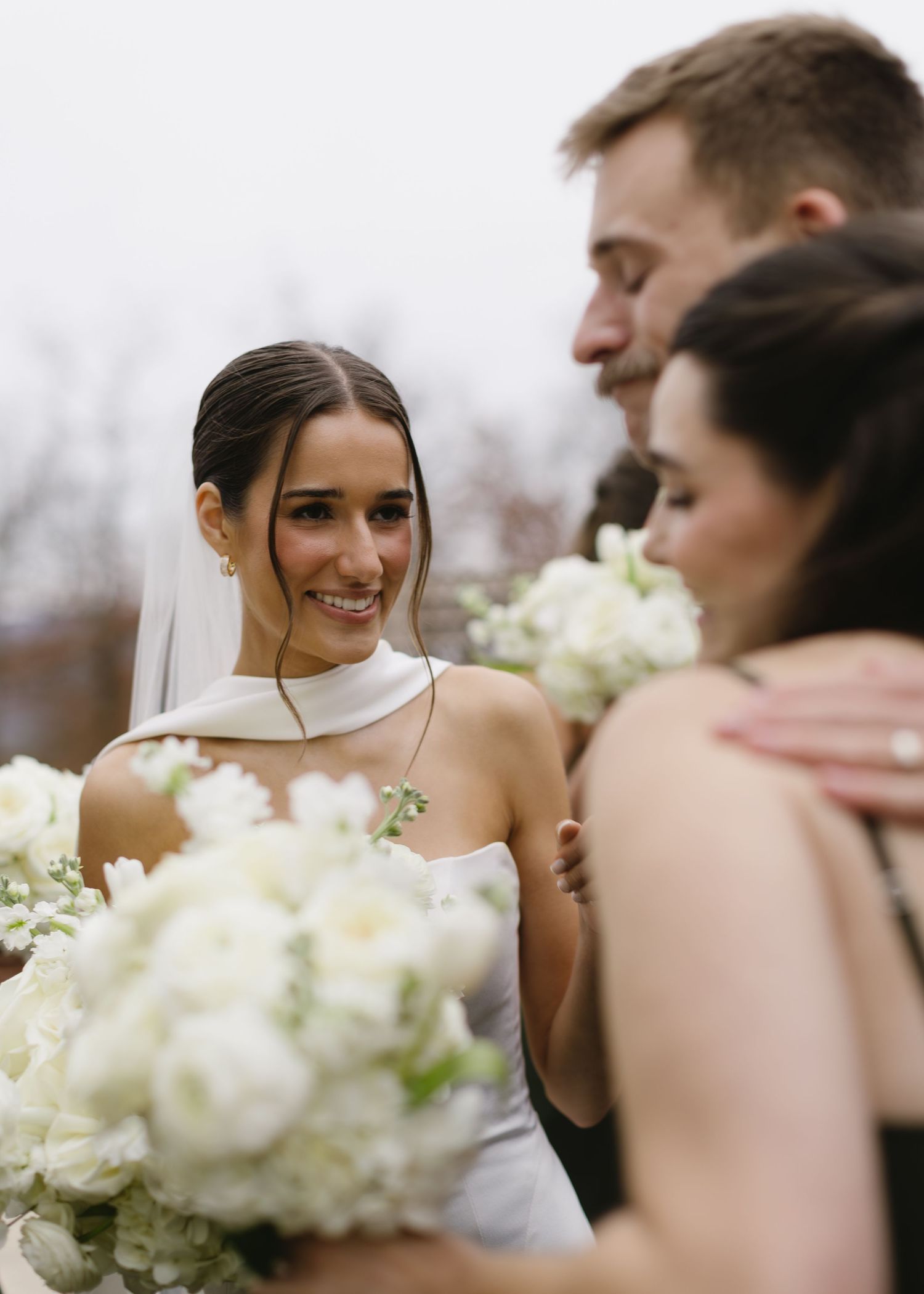 Wedding party shares a joyful moment together with white floral bouquets.