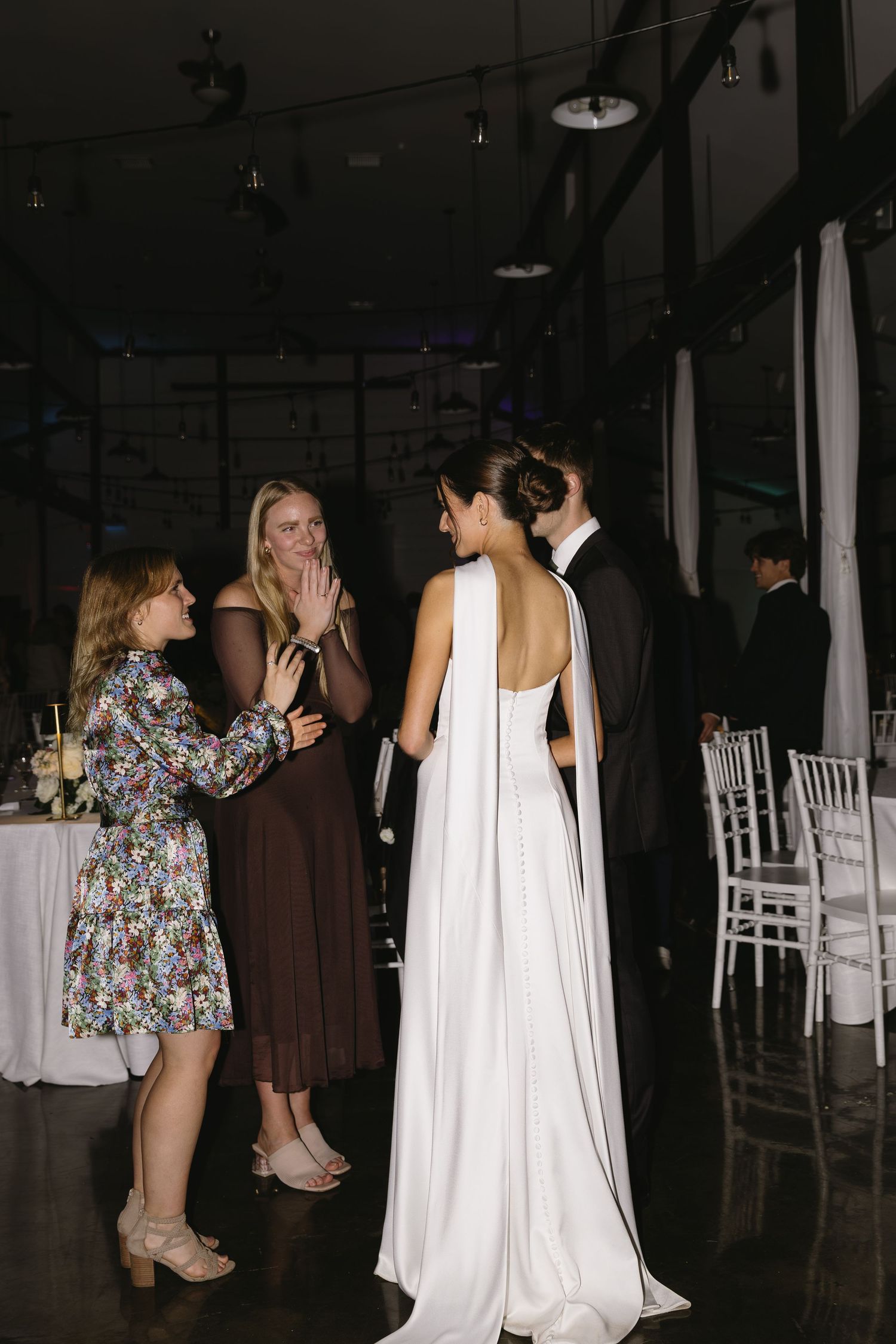 Wedding guests chatting with the bride in her flowing white dress at the reception.