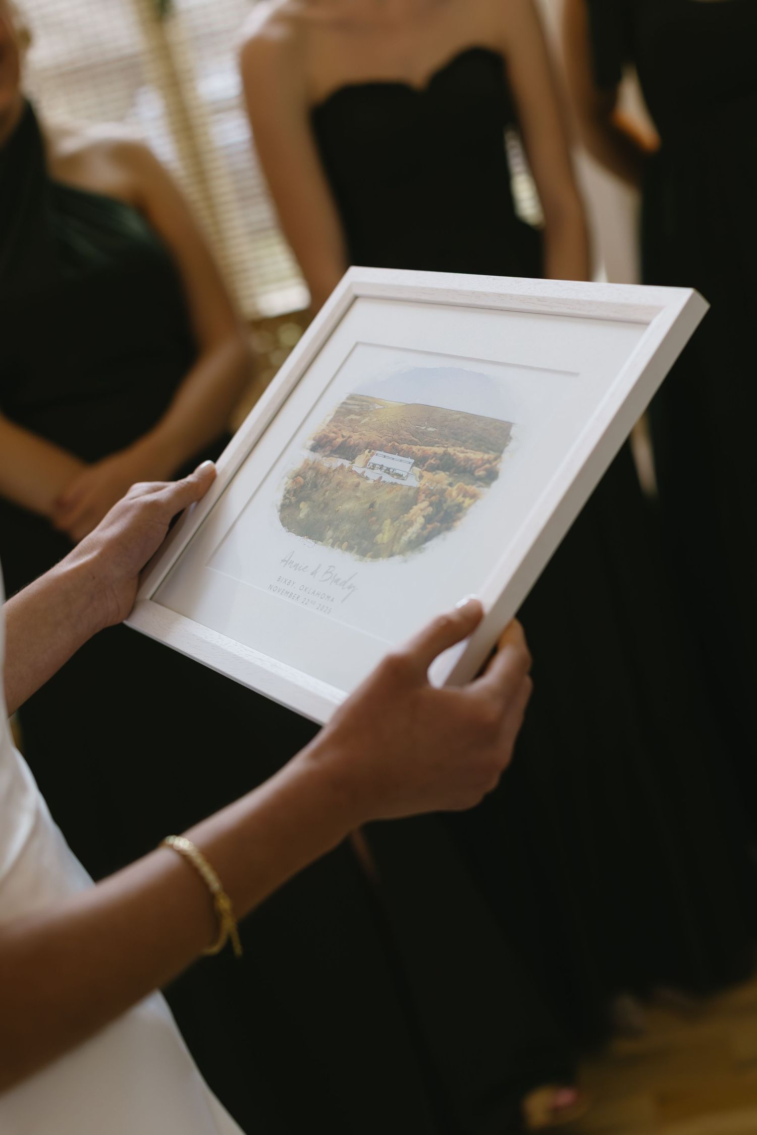 Hands holding an elegant white photo album or book with a landscape image displayed.