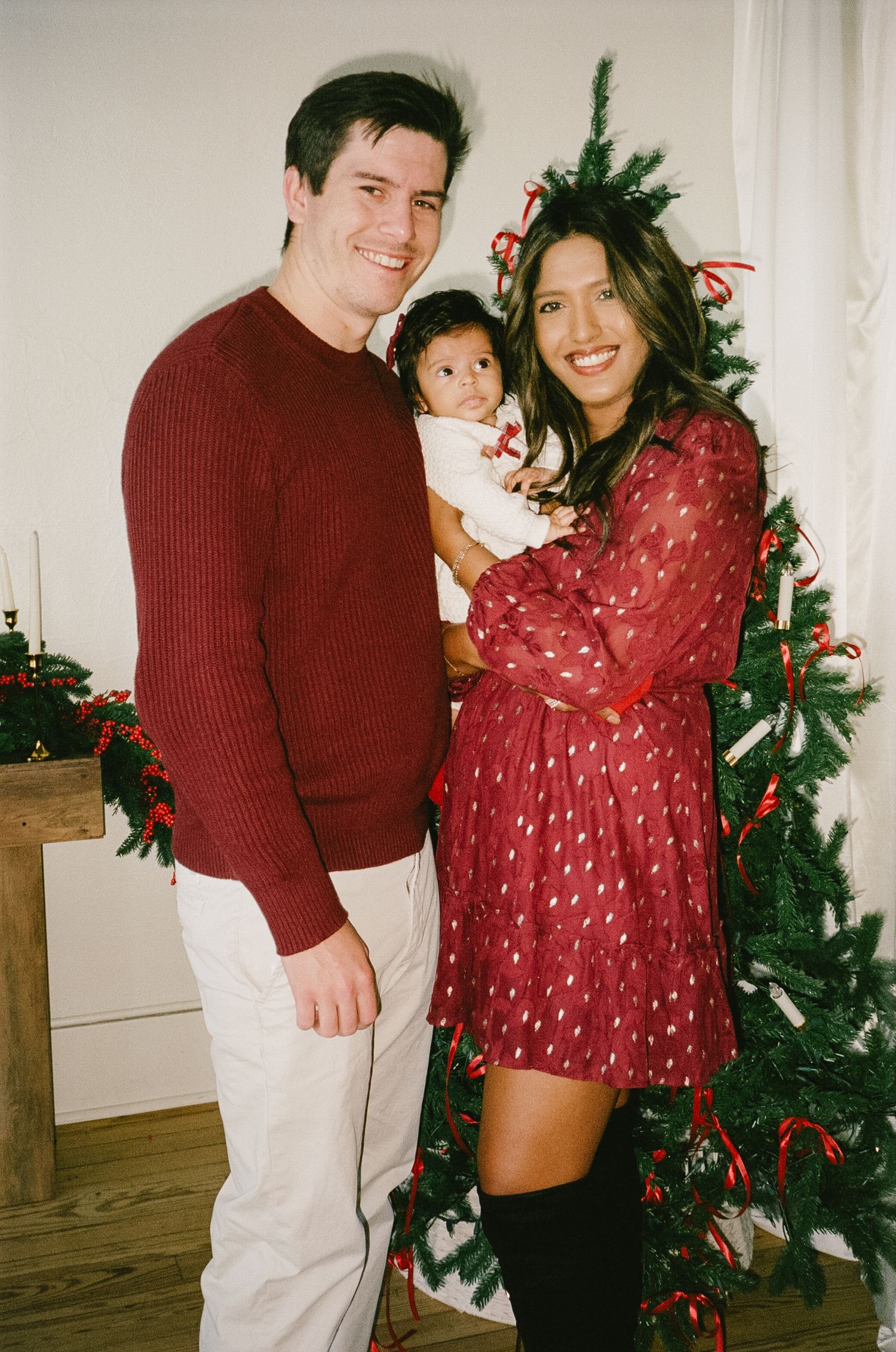 A festive holiday scene with people posing by a Christmas tree in red and white outfits.