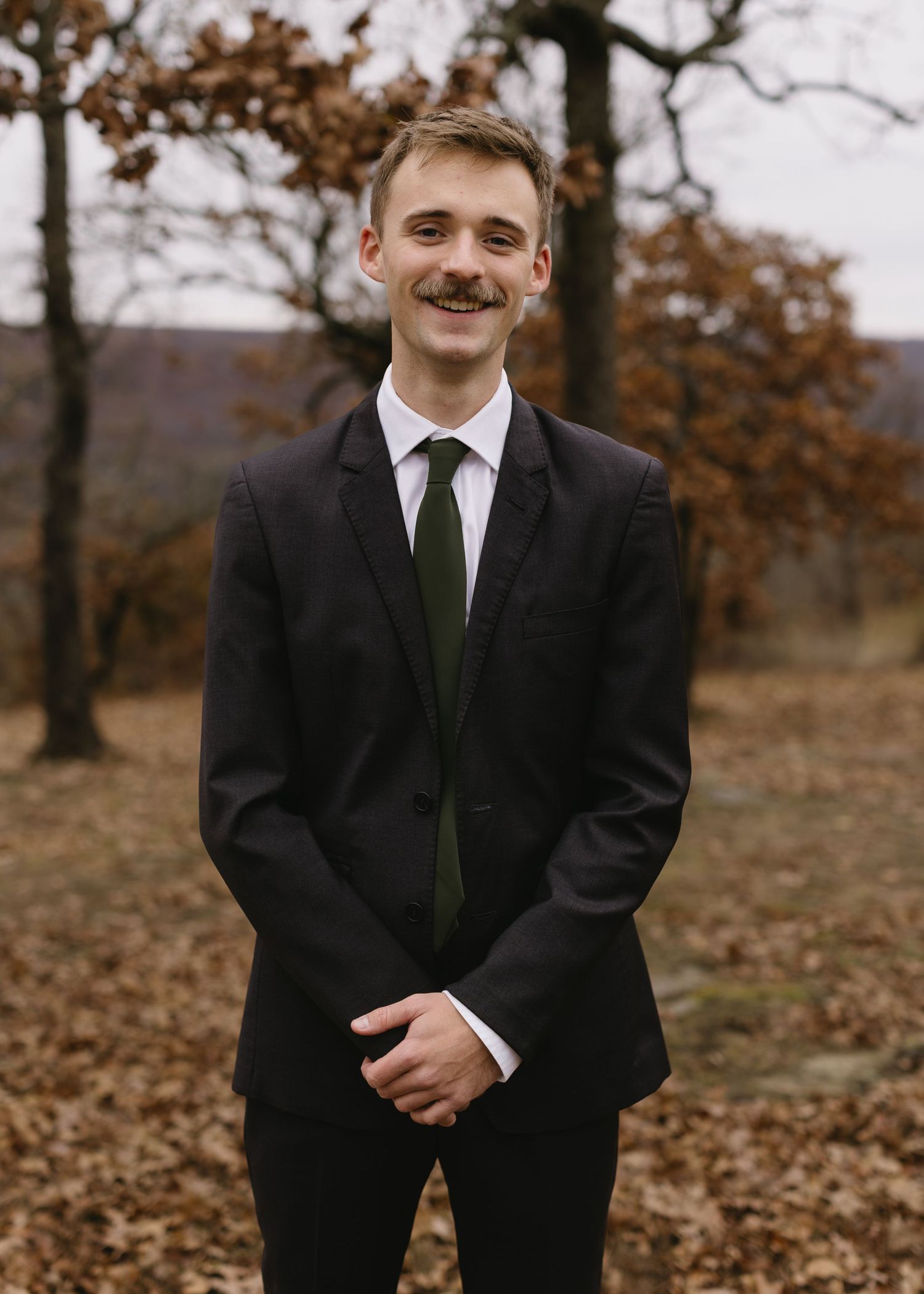 A series of candid portraits showing someone in a black suit and tie against an autumn backdrop with fallen leaves.