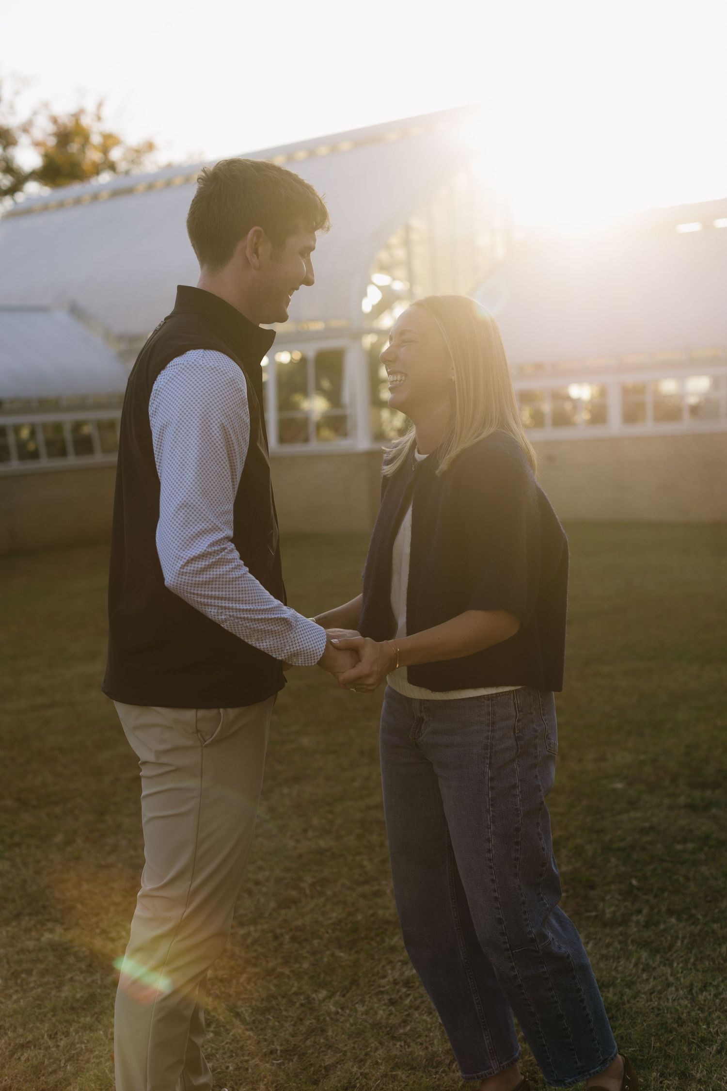 A couple shares a tender moment in golden sunlight on a grassy field.