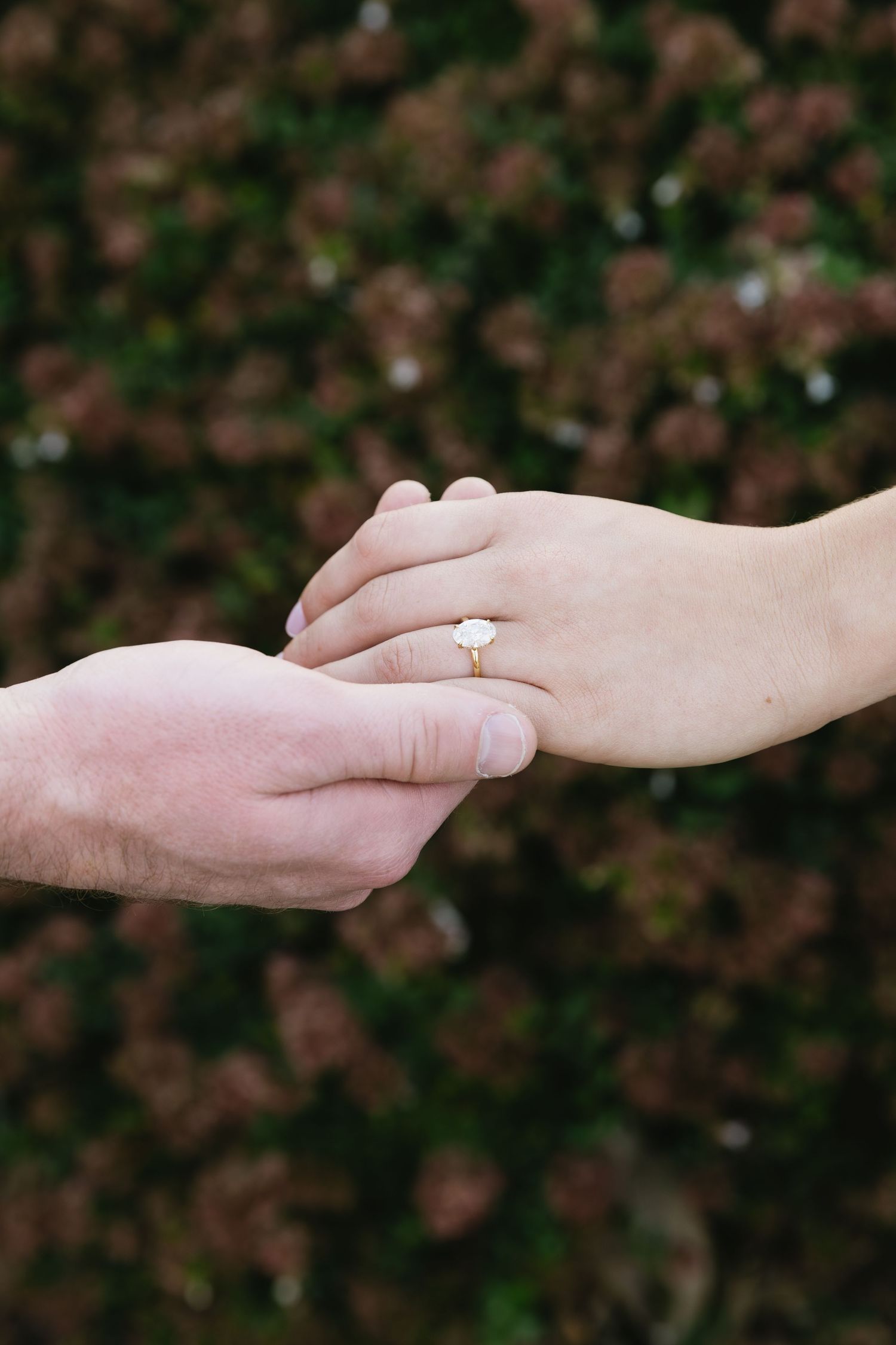 Close-up of hands with engagement ring showing tender moment between couple.