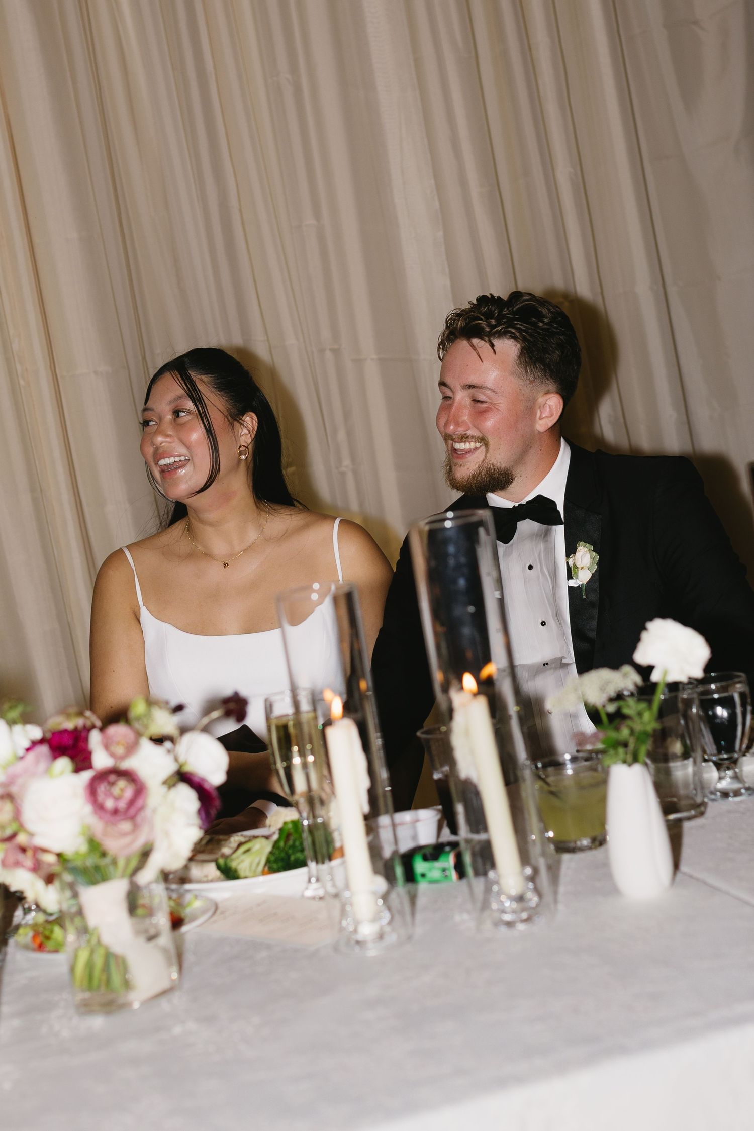 Wedding couple shares laughter at the head table during their reception dinner.