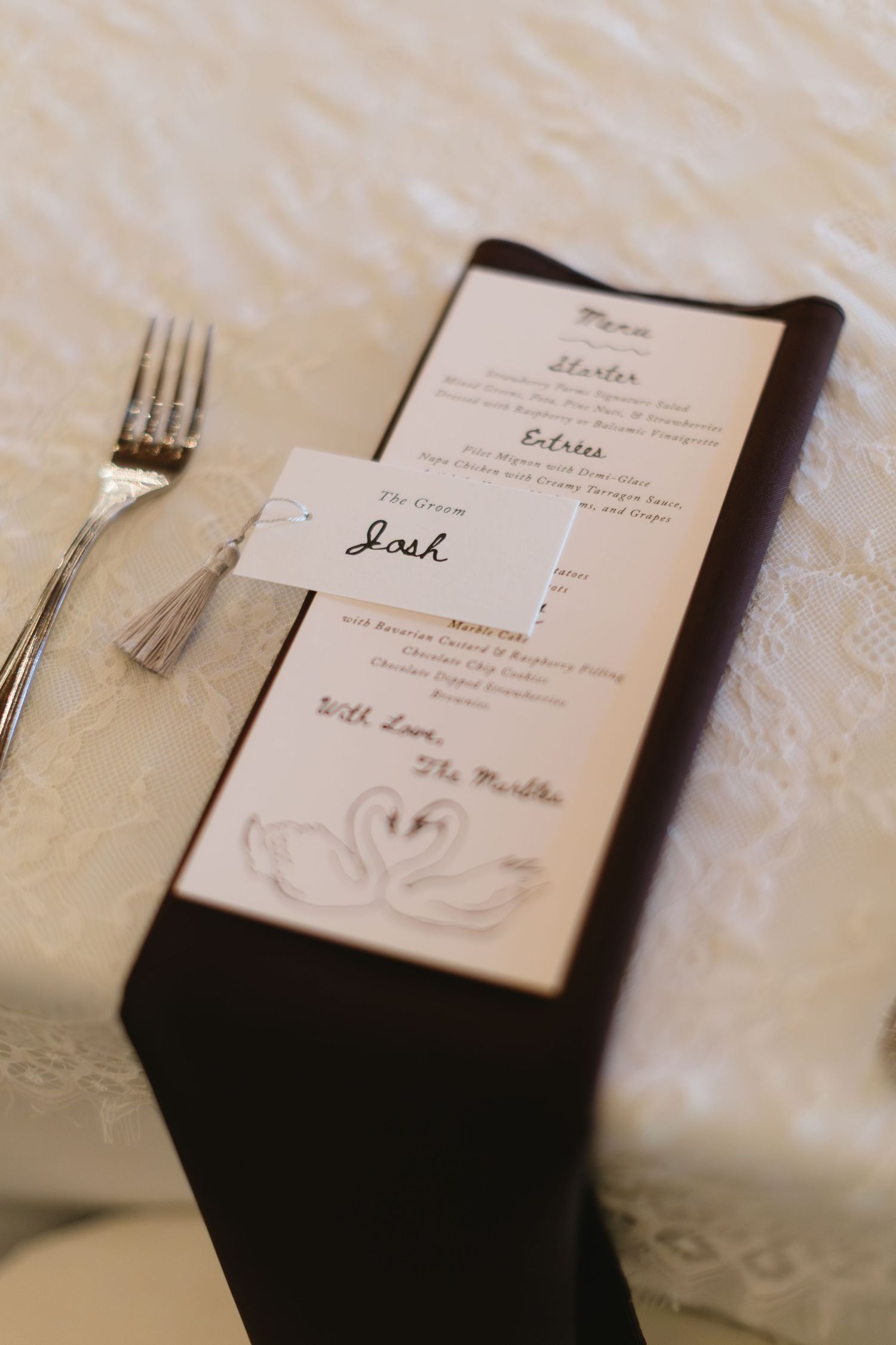 Elegant wedding place settings with menu cards and silverware on white tablecloths.