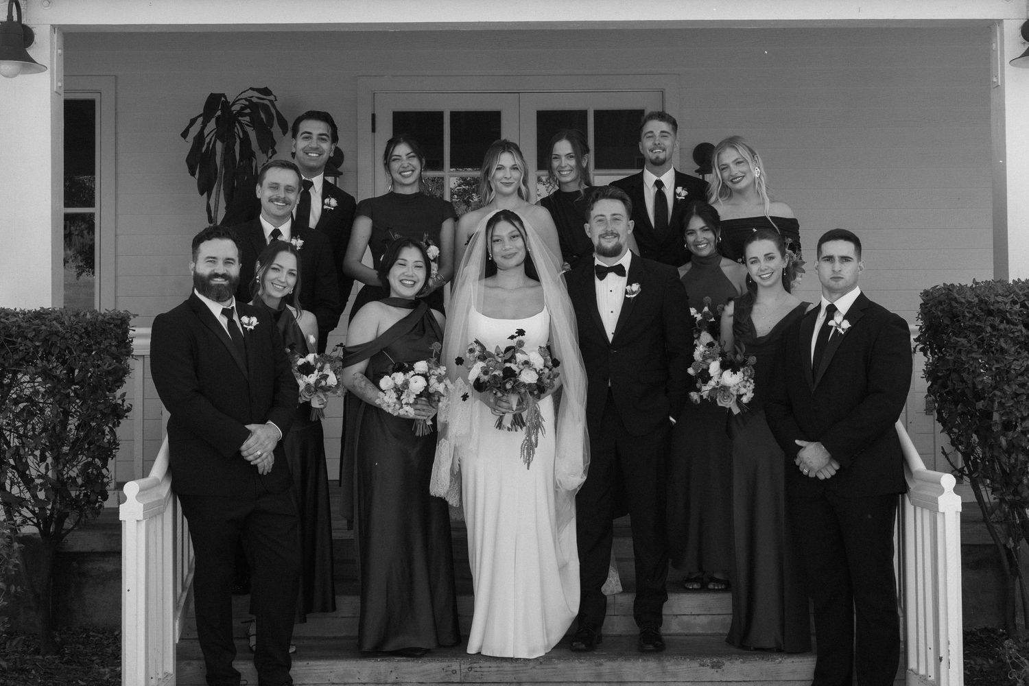 Black and white formal wedding party portrait in front of a traditional building.
