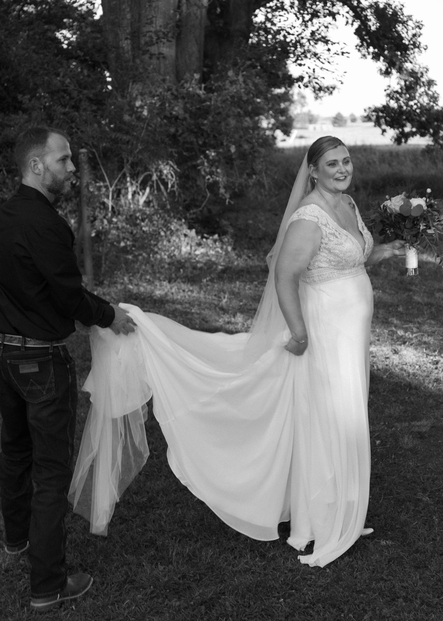 Wedding party poses outdoors with flowing white dress movements in natural lighting.