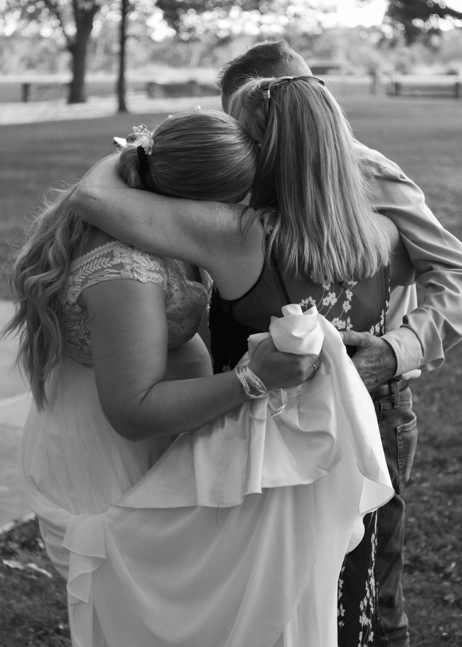 Black and white candid moment of a couple embracing during a celebration.