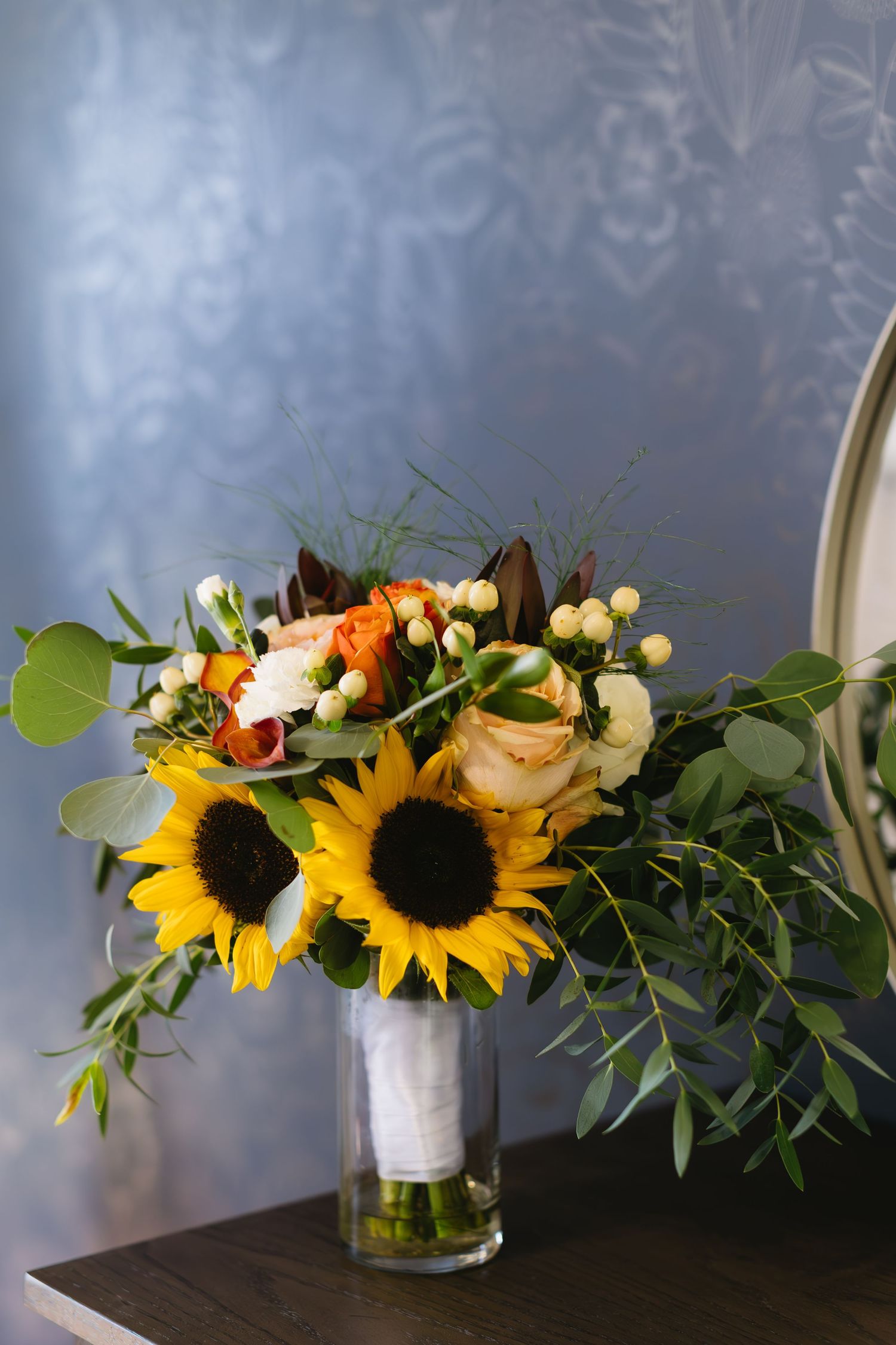 Elegant floral arrangements with sunflowers and mixed flowers in glass vases against a dark background.