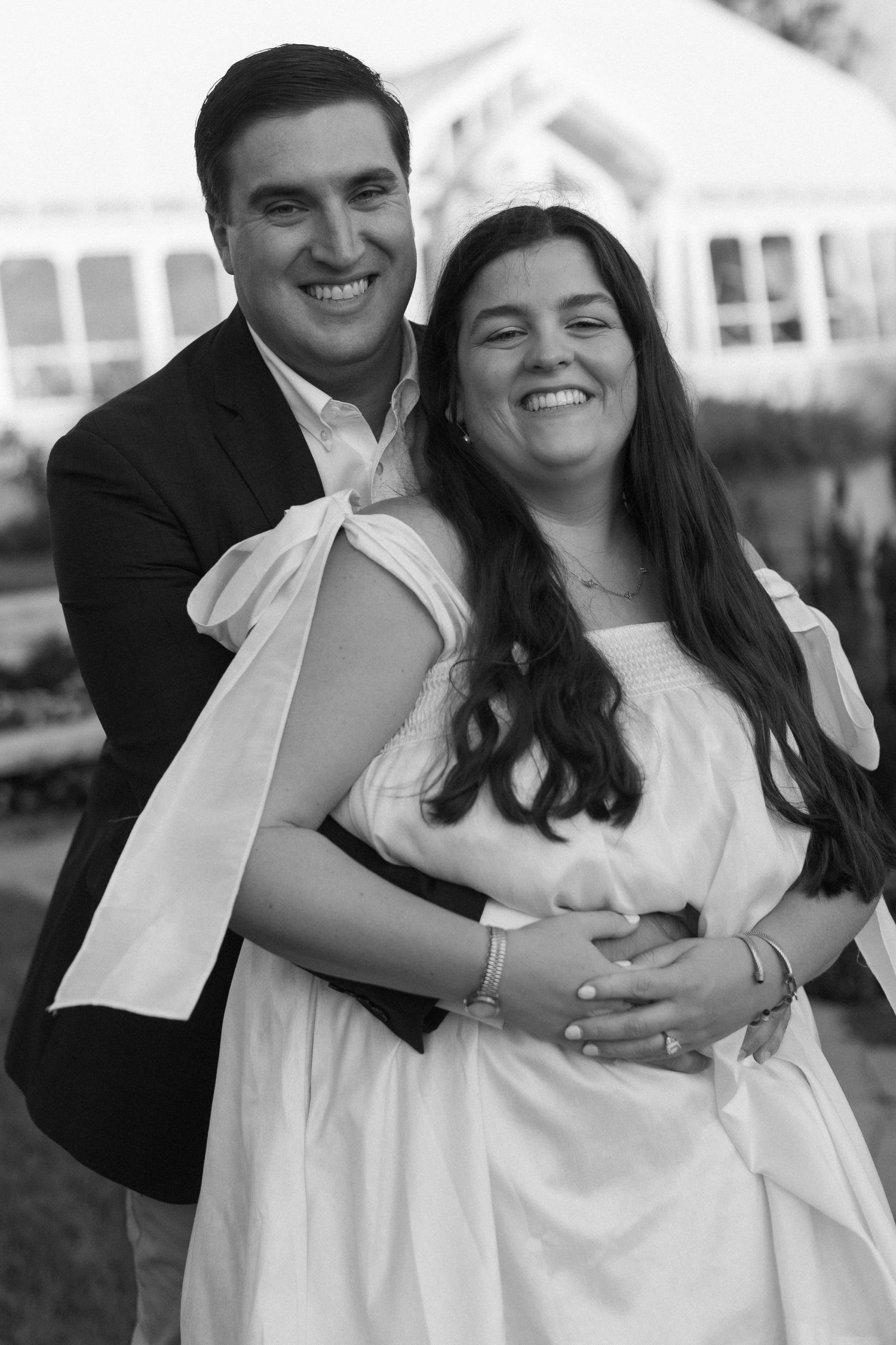Black and white photos of a joyful couple embracing and laughing together outdoors.