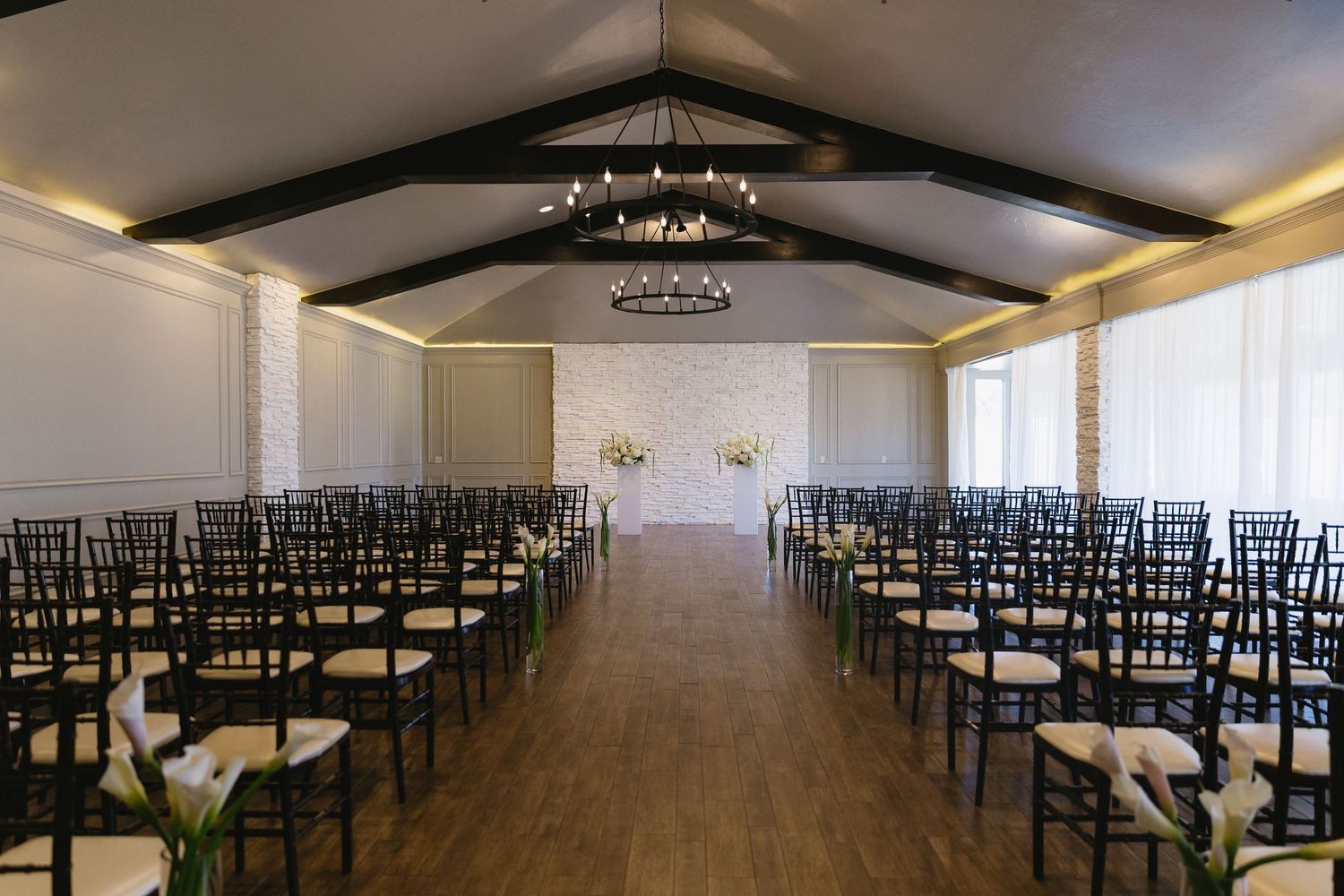 Modern wedding venue with rows of black chairs and vaulted ceiling.