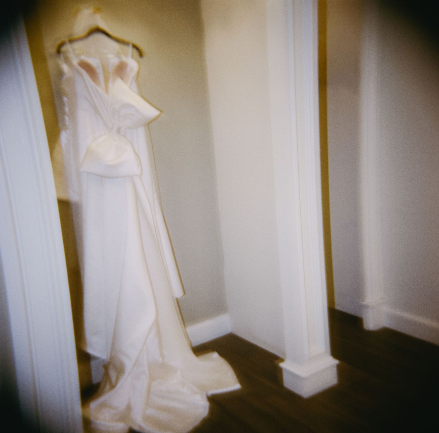 Row of elegant white wedding dresses displayed on hangers in a softly lit room.