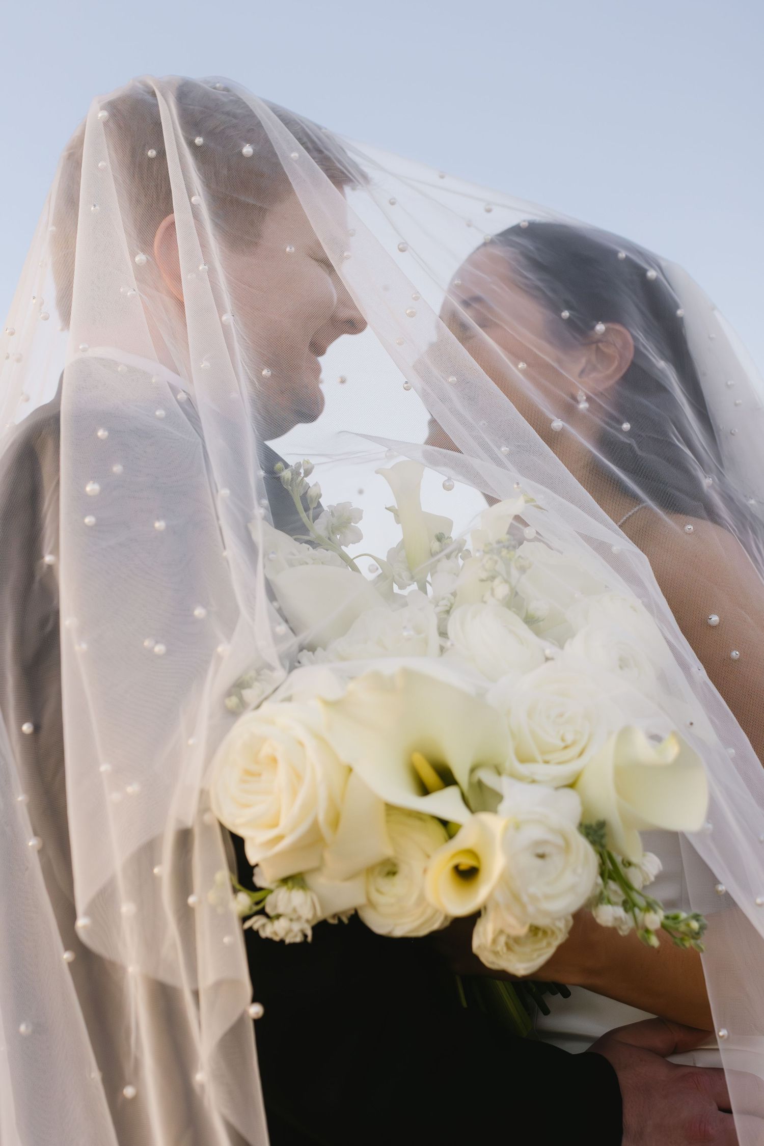 White roses adorn a delicate bridal veil in an artistic close-up shot.