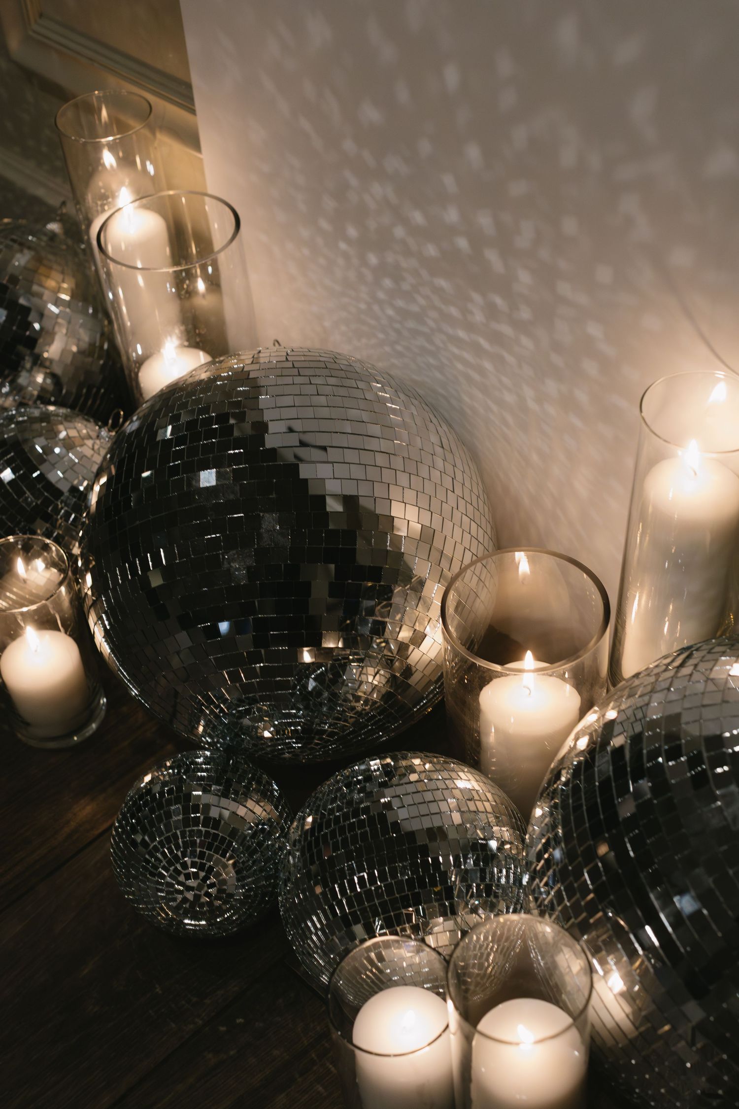 Disco balls and glowing candles create a romantic party atmosphere with sparkling reflections on the wall.