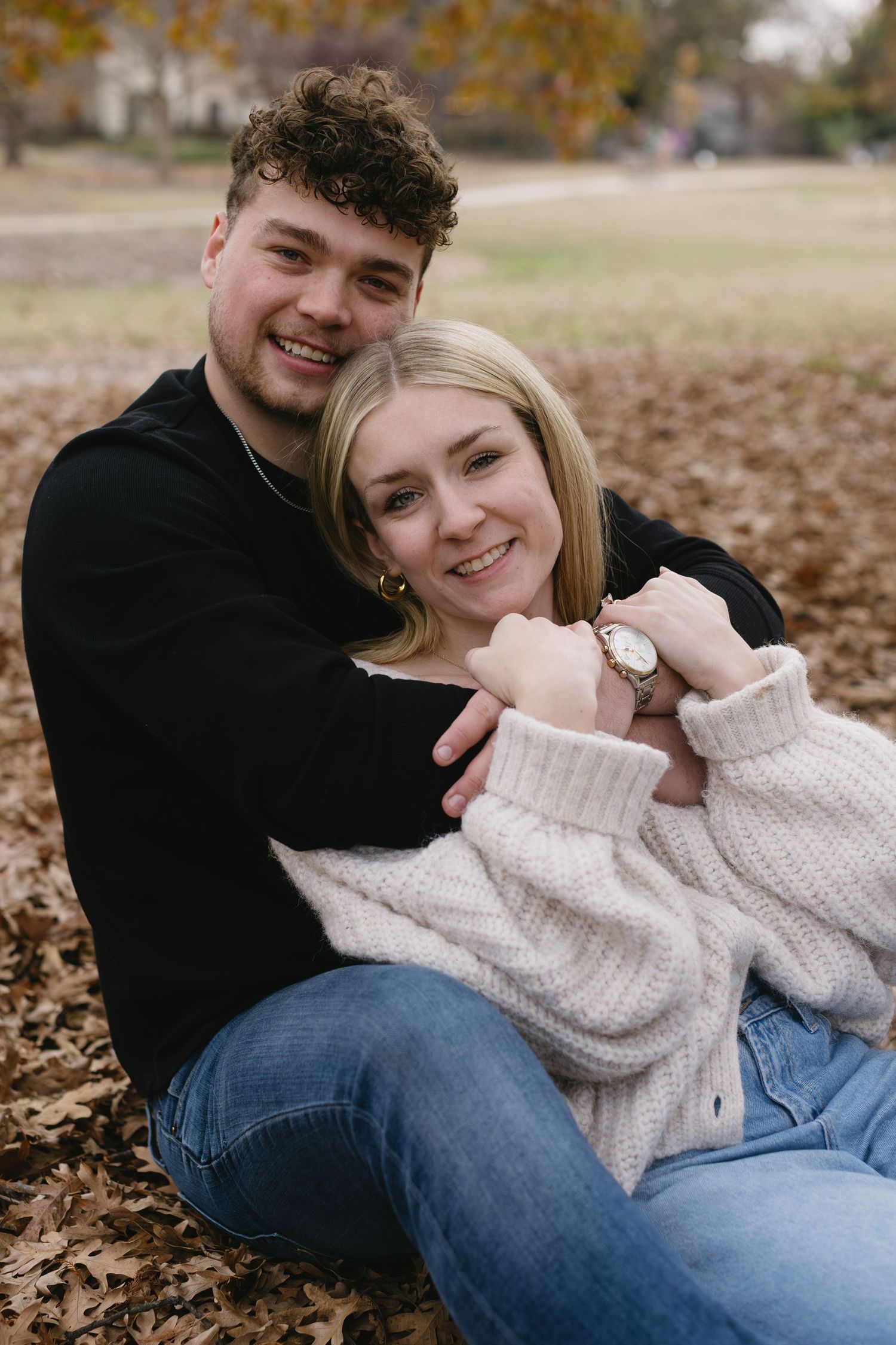 A couple lounges together on autumn leaves during a romantic outdoor photoshoot.