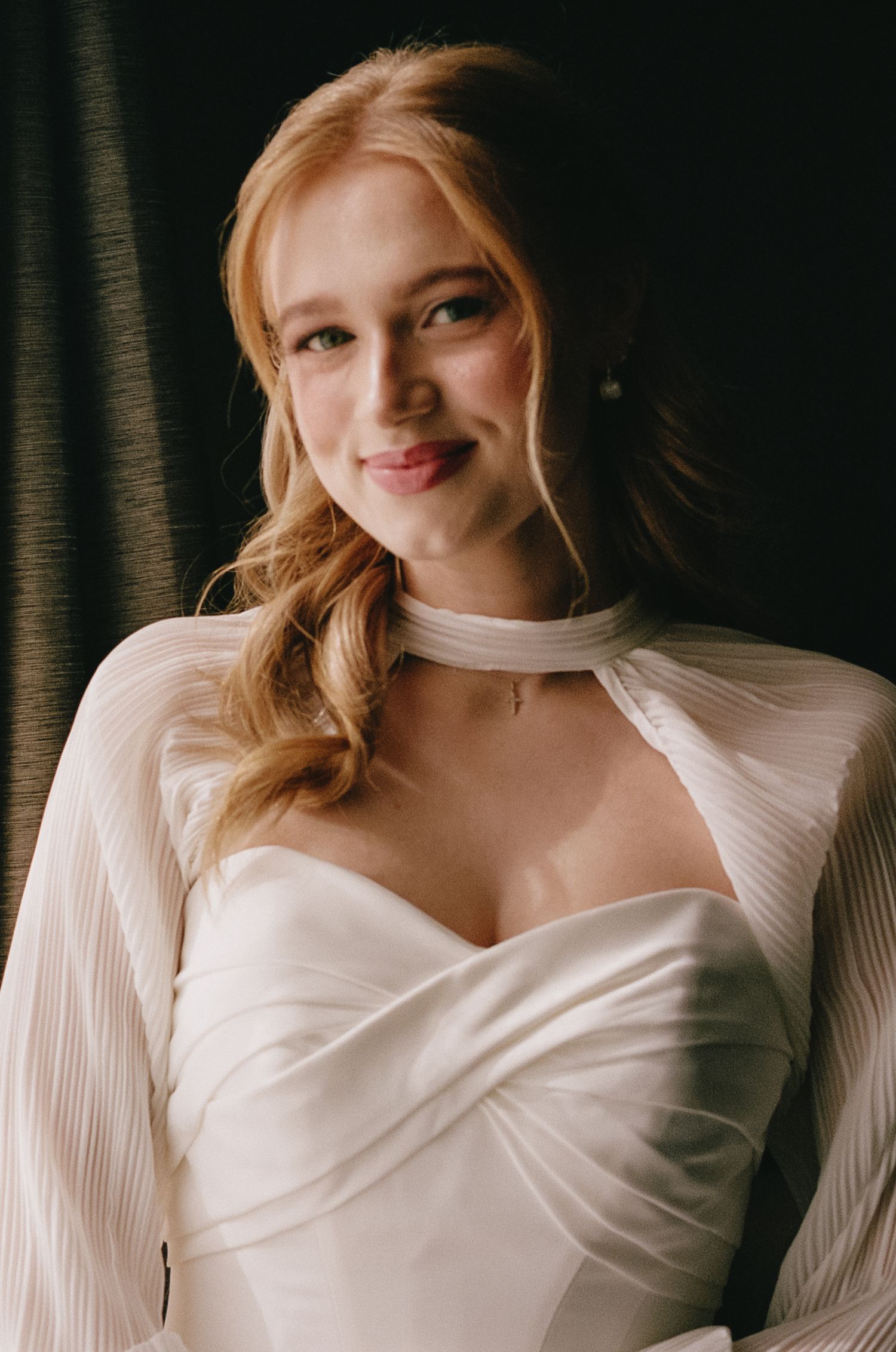 Close-up portrait of bride in pleated white wedding dress.
