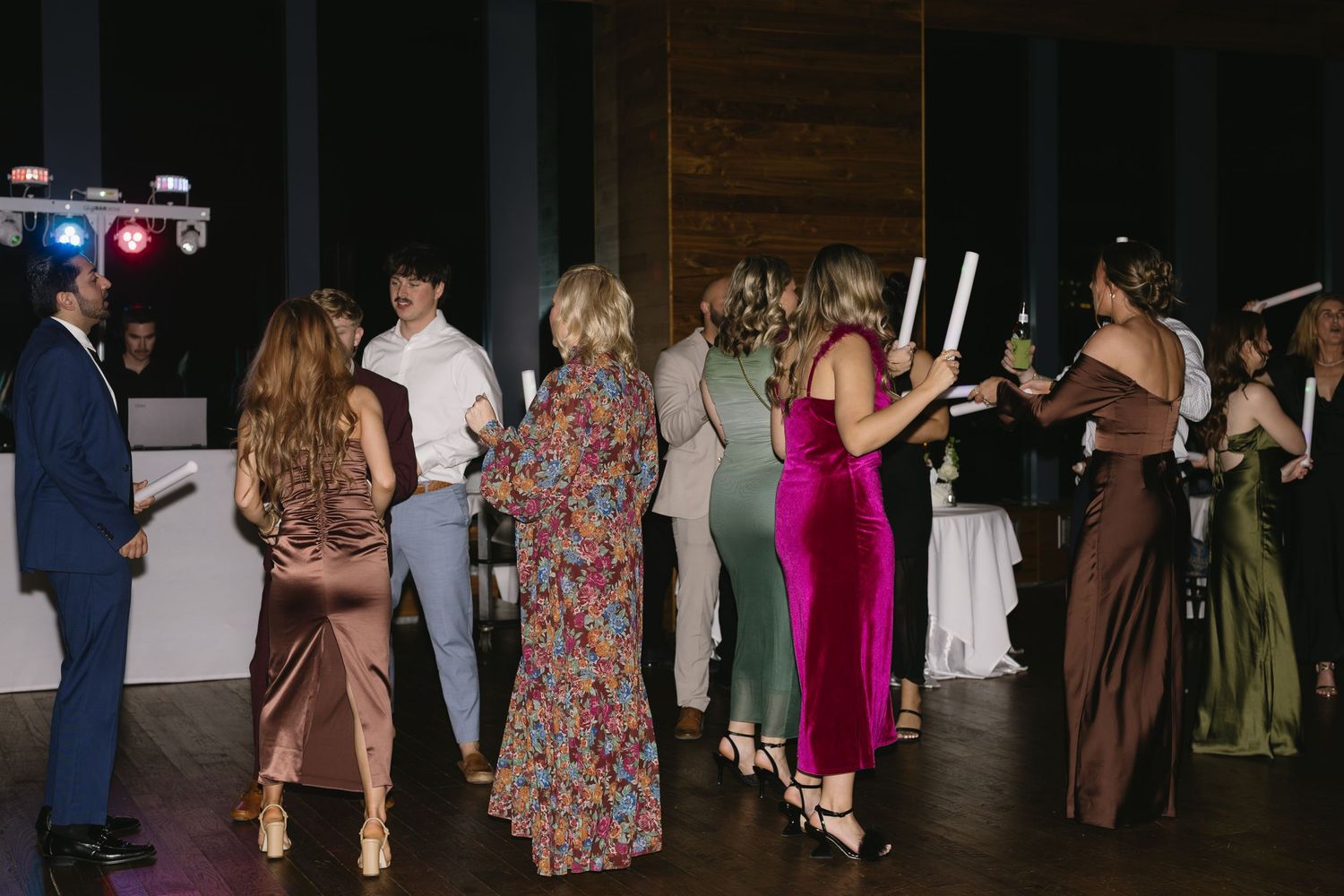 Wedding guests dancing together on a dark dance floor at an evening reception celebration.