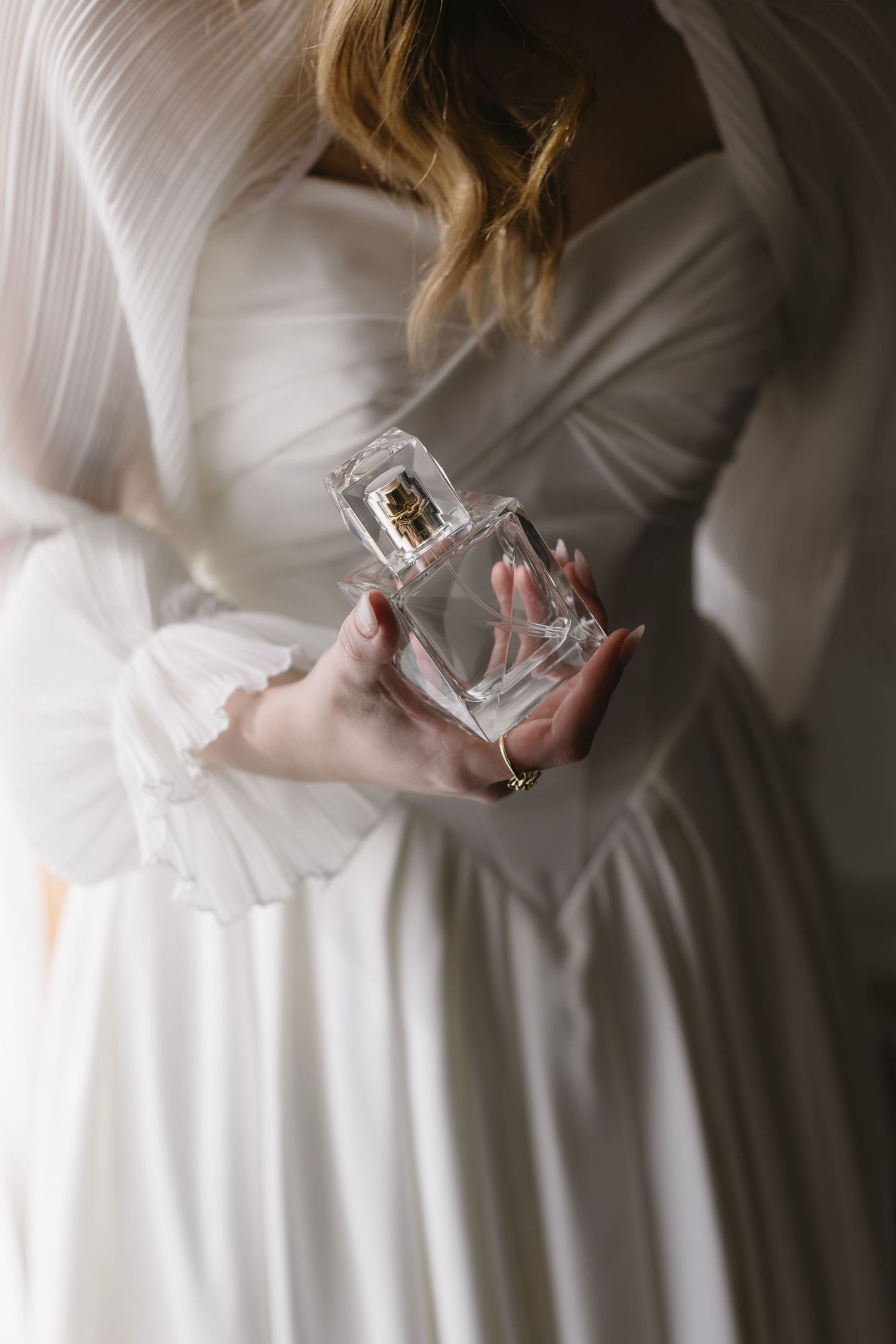Elegant bridal detail shots showing perfume bottle and white wedding dress.