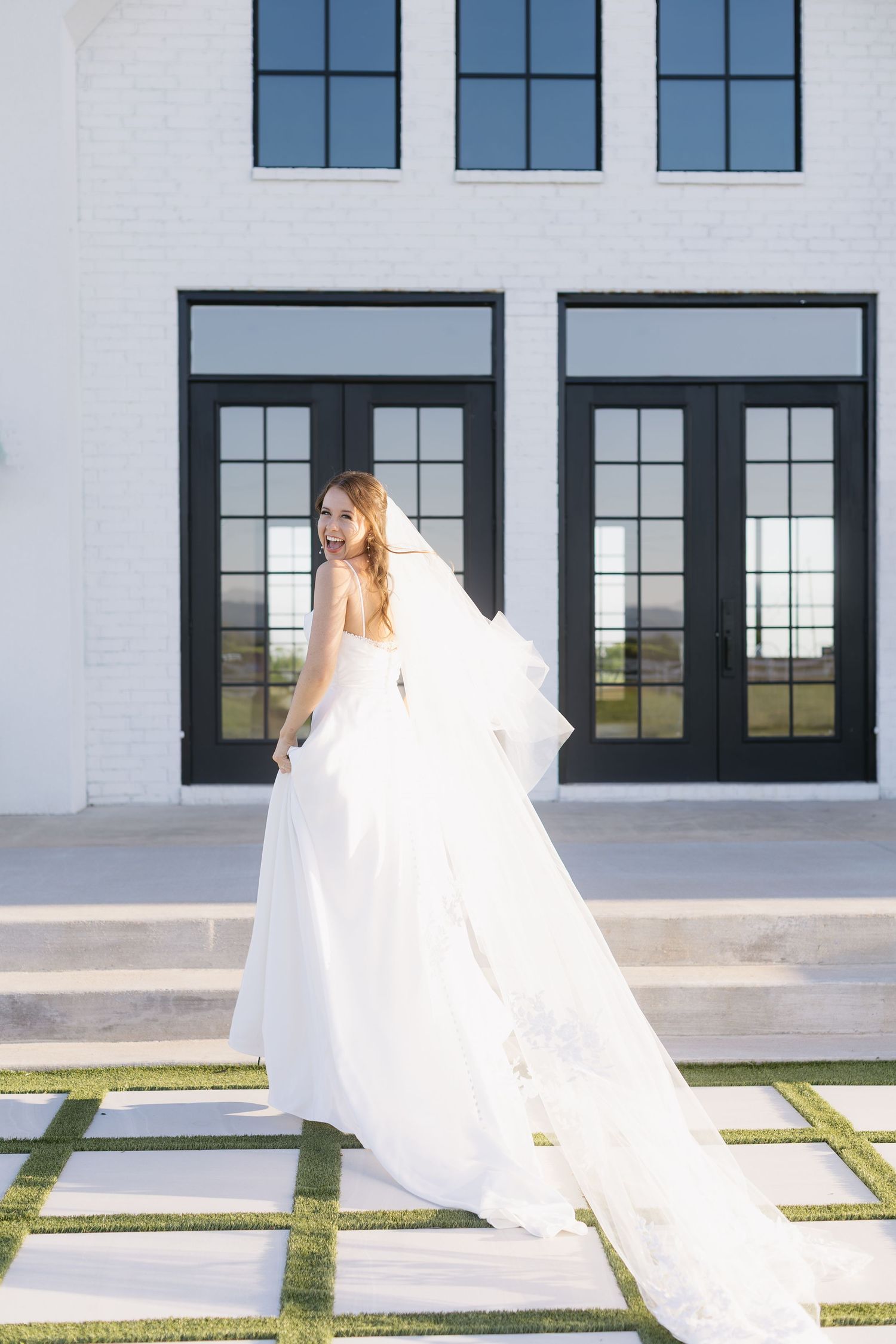 Multiple shots of a bride in motion outdoors against a white building with dramatic black window frames.