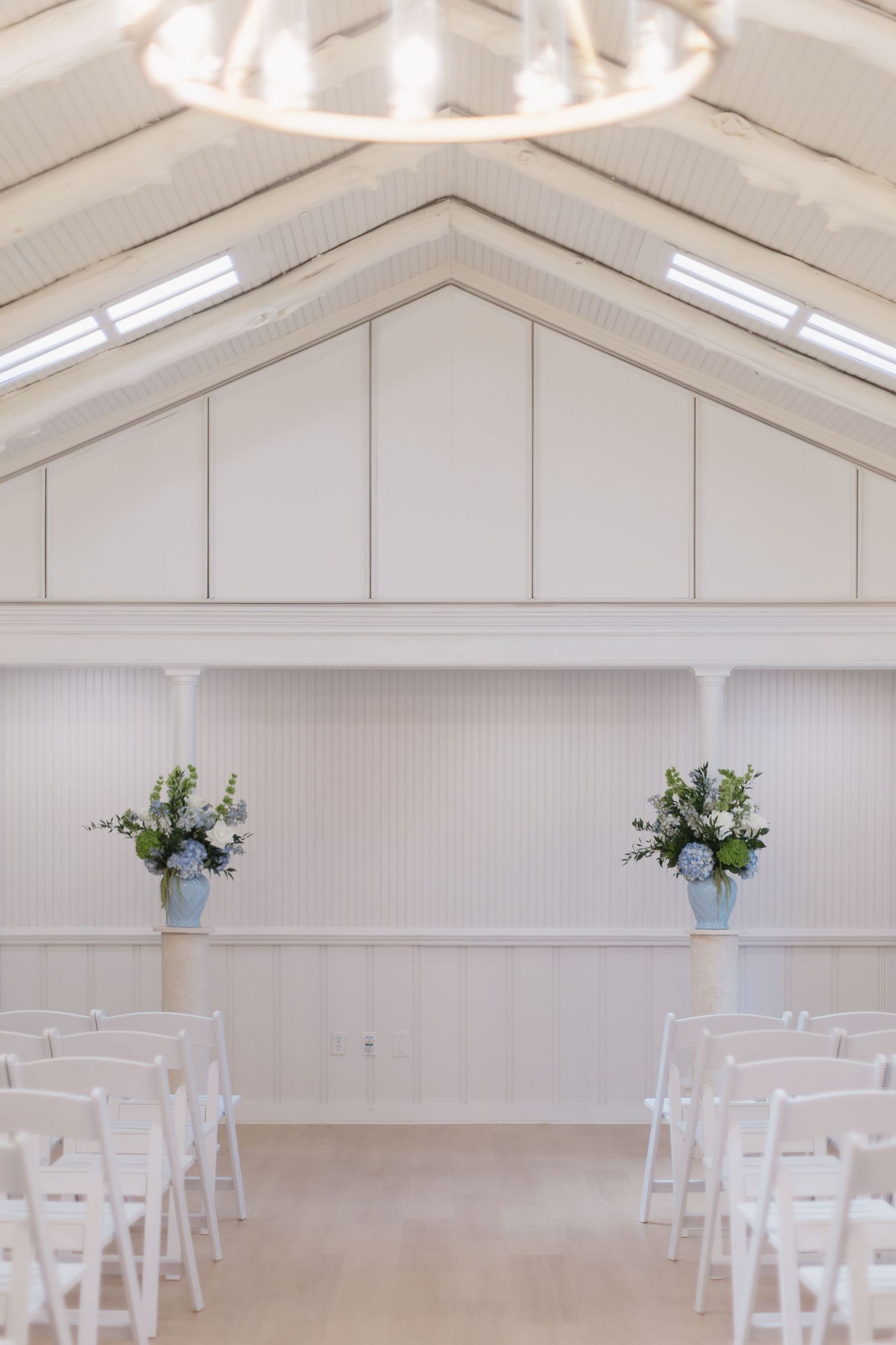 Clean white wedding chapel interior with vaulted ceiling and rows of white chairs arranged for a ceremony.