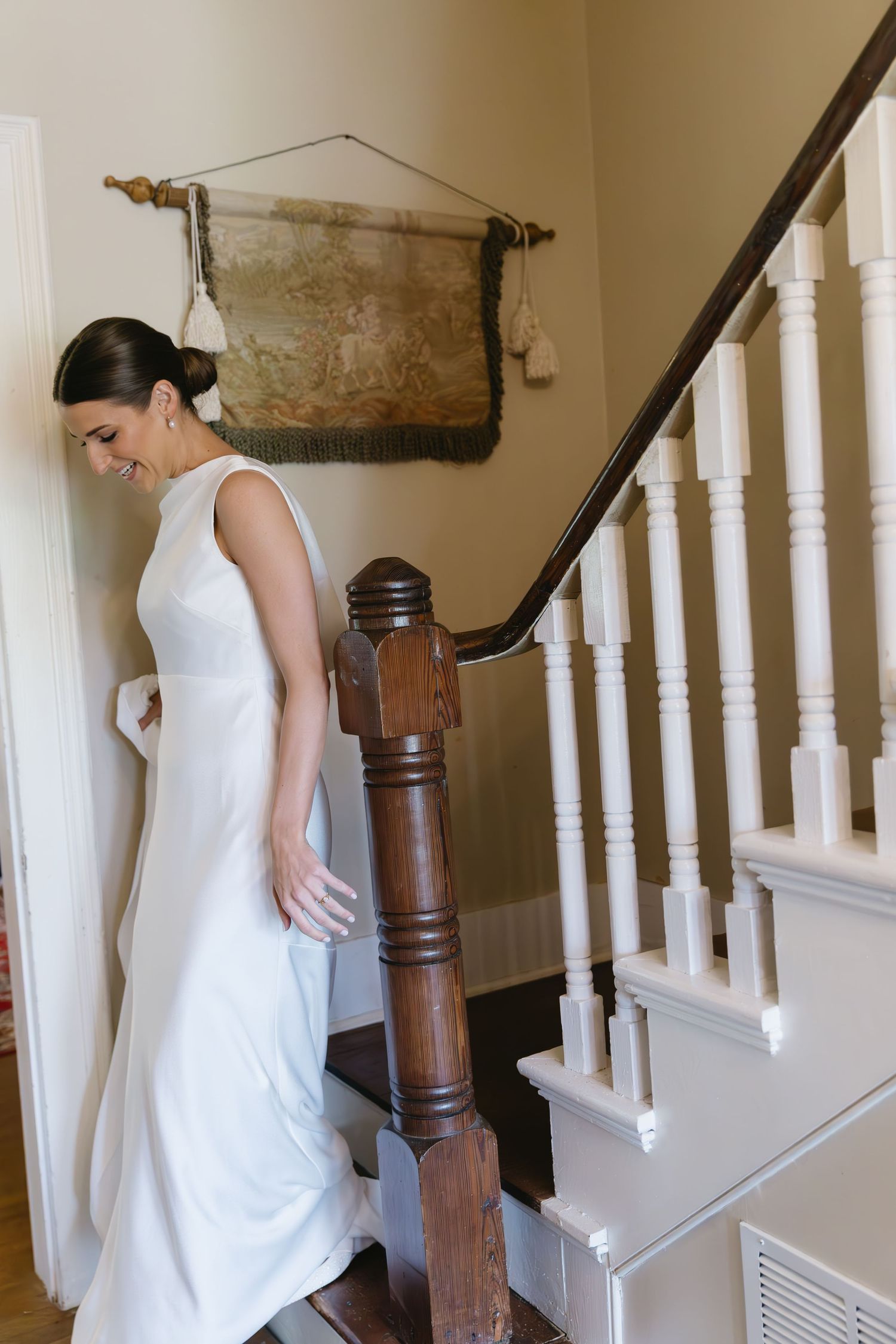 Classic white dress seen against wooden staircase with white balusters in a bright interior setting.