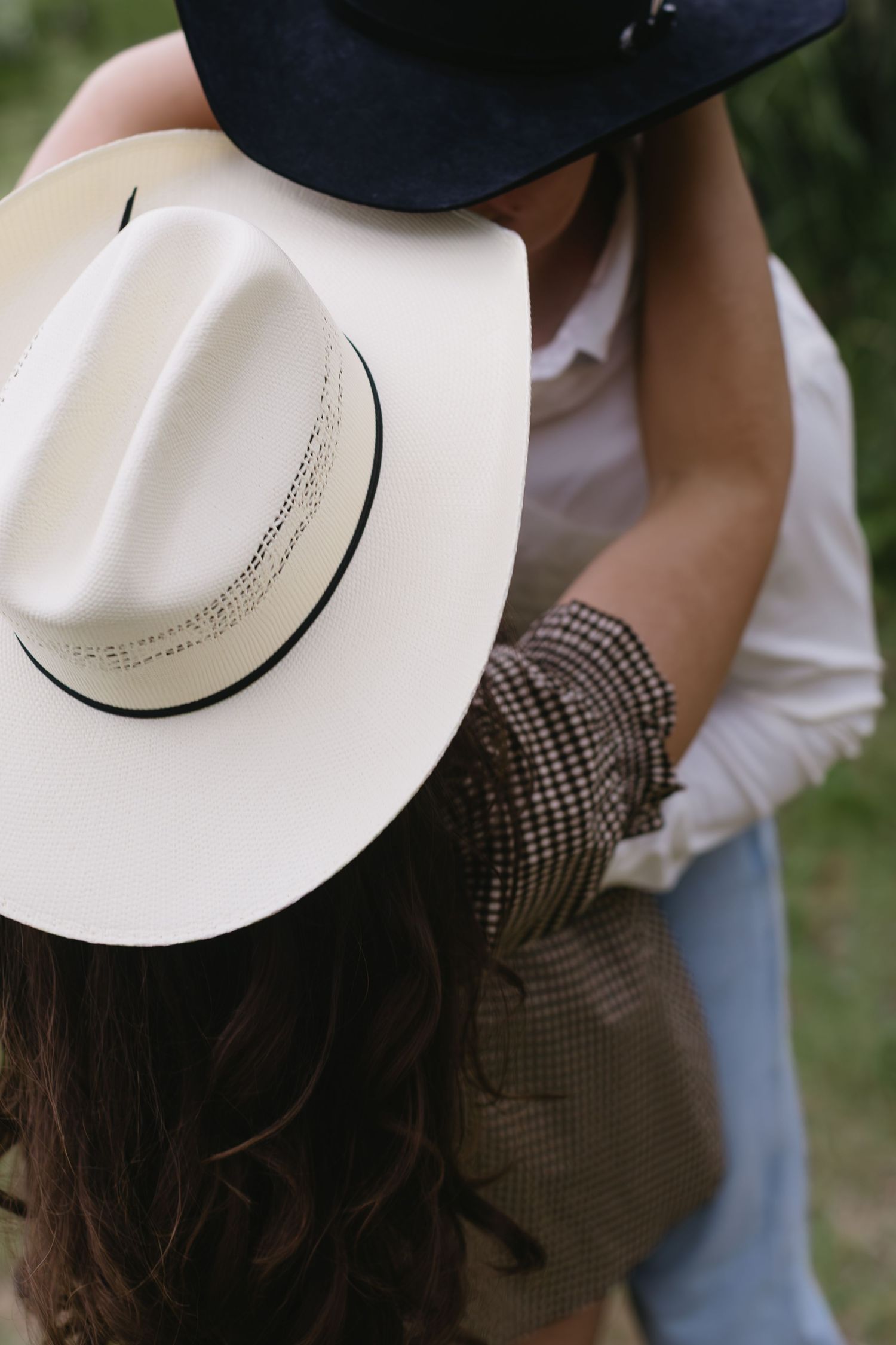 Close-up view of black and white cowboy hats as couple shares an intimate moment.