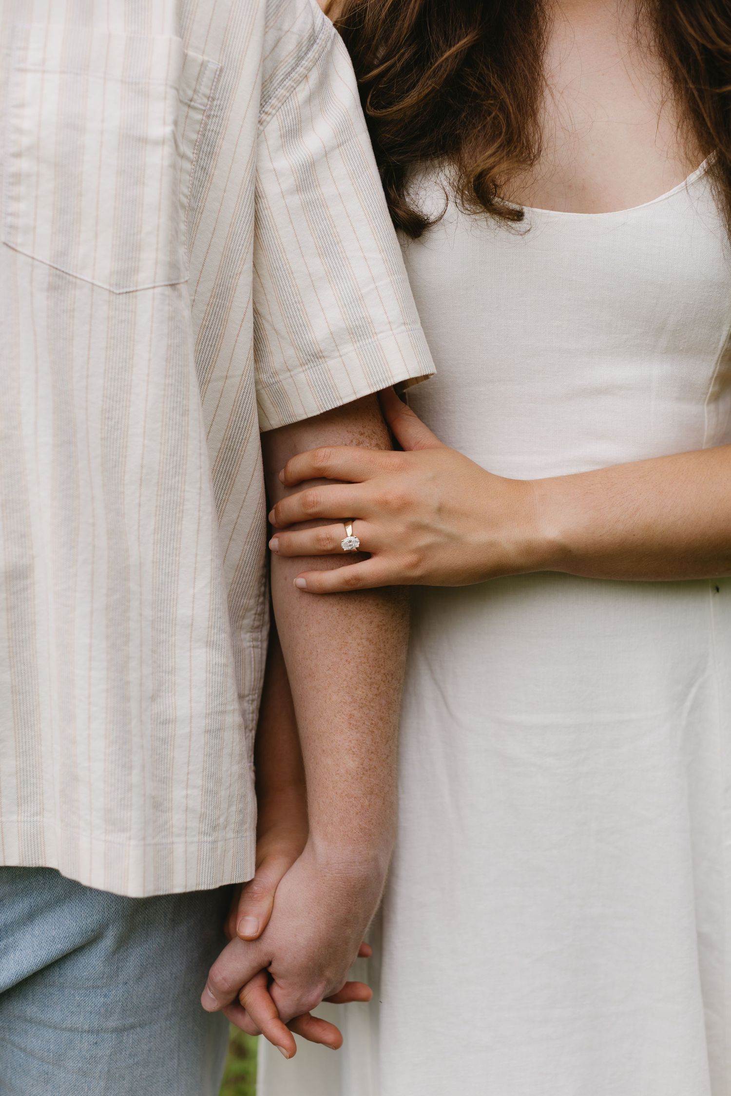 Close-up series showing intimate hand-holding moments between a couple wearing white and cream colored clothing.