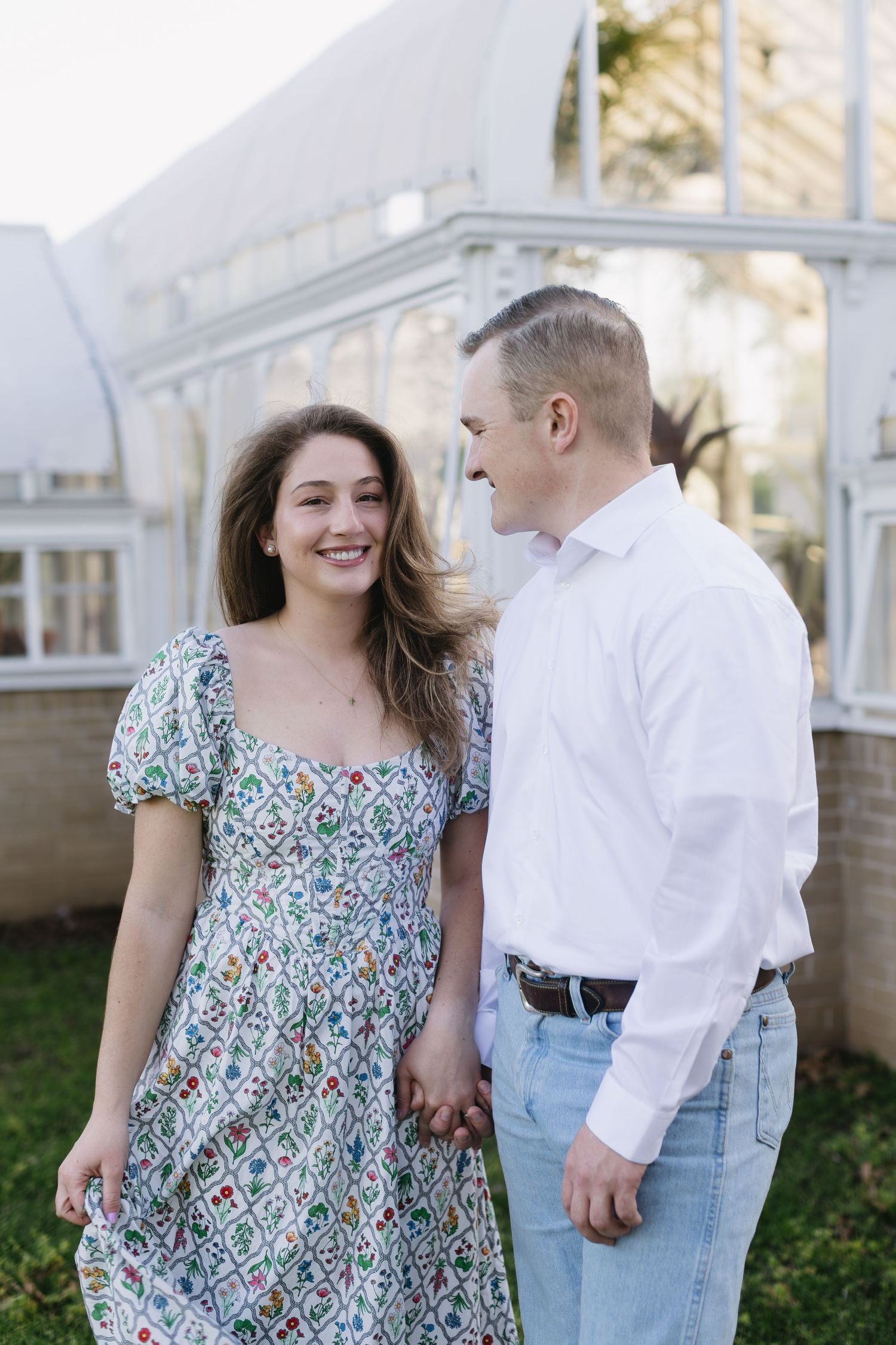 A couple shares tender moments together while wearing coordinating outfits of a floral dress and white shirt with jeans.