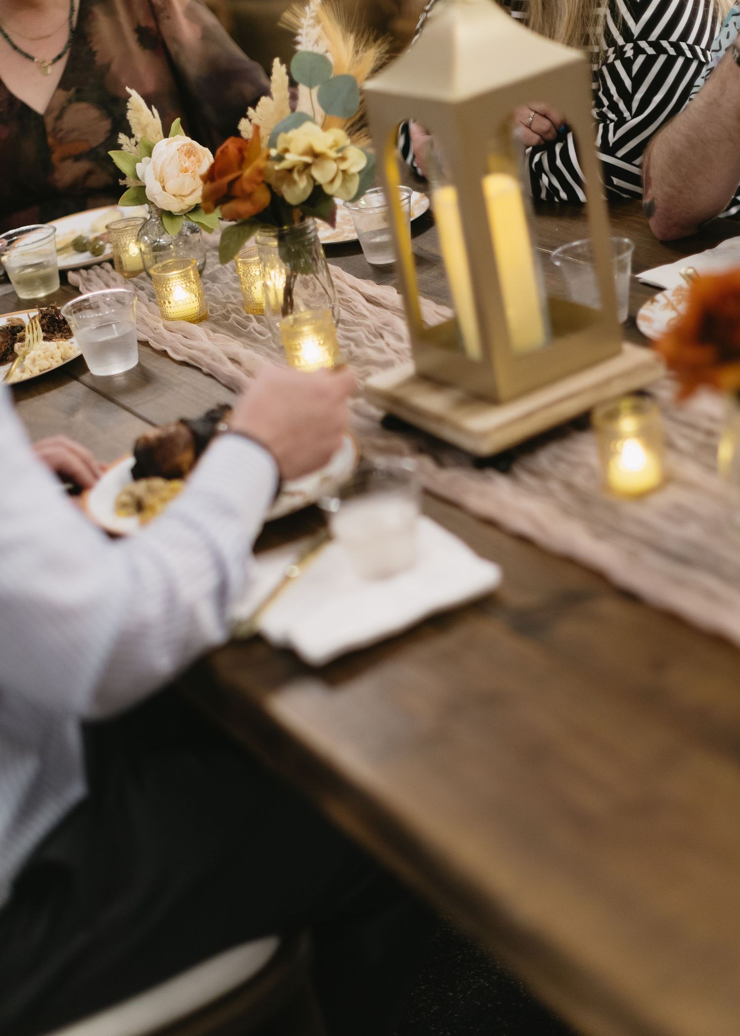 Elegant wedding table setting with lanterns, candles and floral centerpieces.