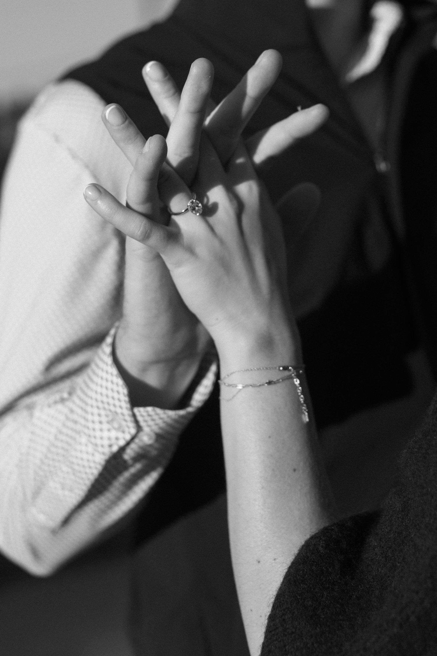 Black and white close-up of hands with delicate jewelry.