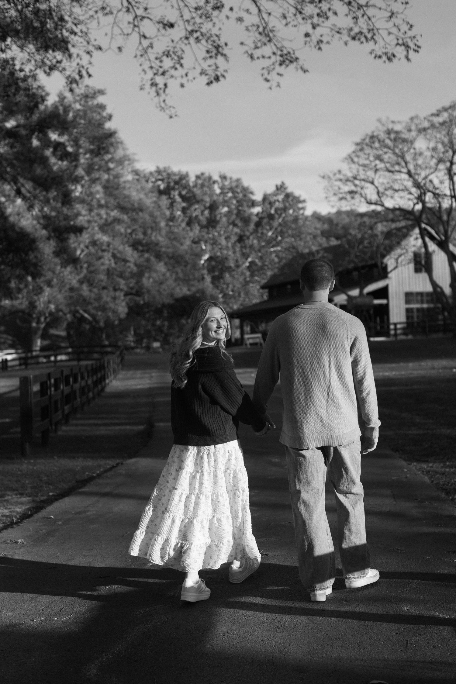 Black and white photos of a couple walking together on a tree-lined path.